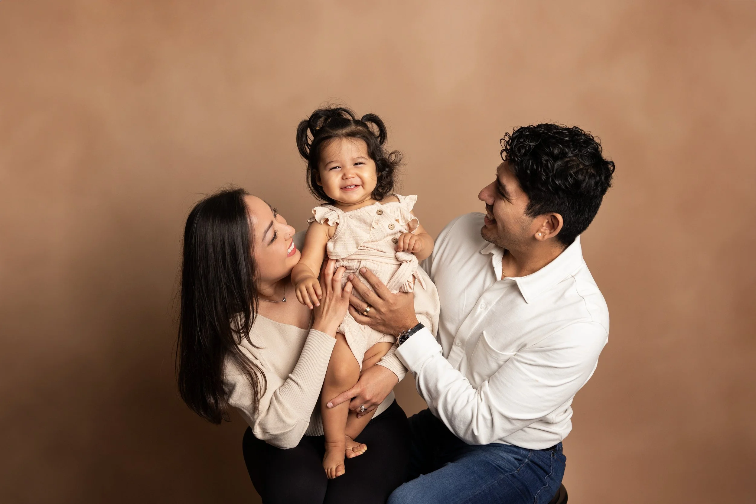 Parents holding their smiling toddler during a family milestone photography session in Austin Texas.