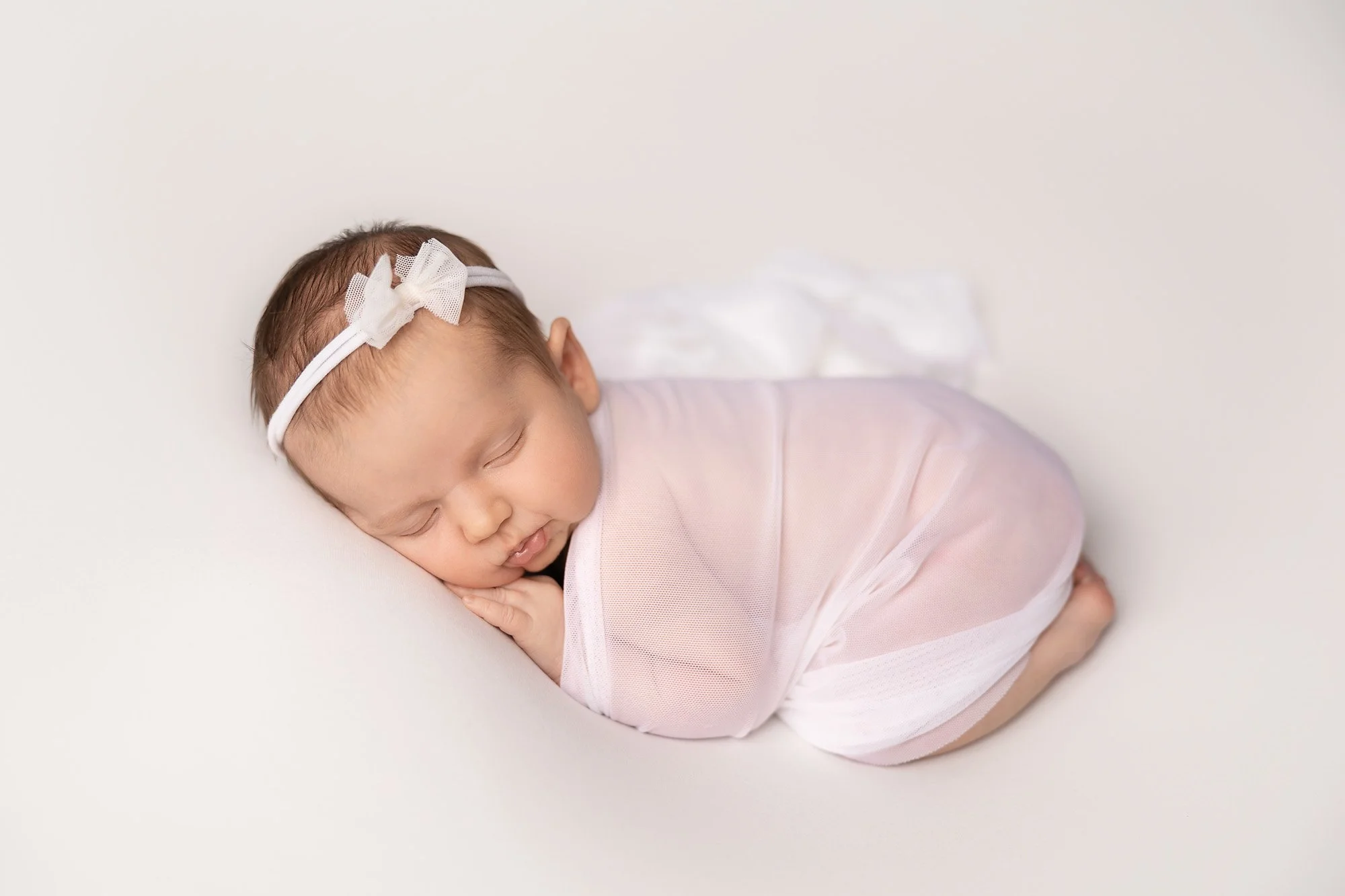 newborn baby girl in bum-up pose with sheer white wrap