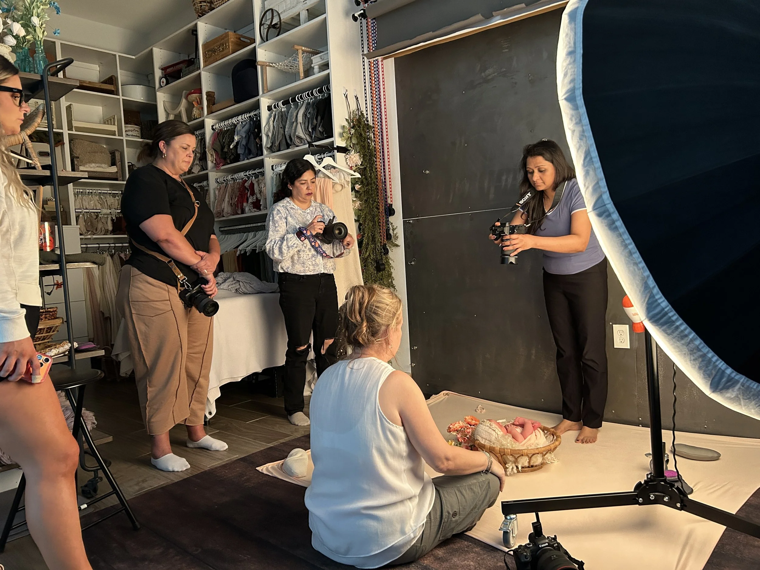 Photographers attending a hands-on newborn photography workshop in Jessica Doffing's Austin studio learning posing, lighting, and composition techniques.