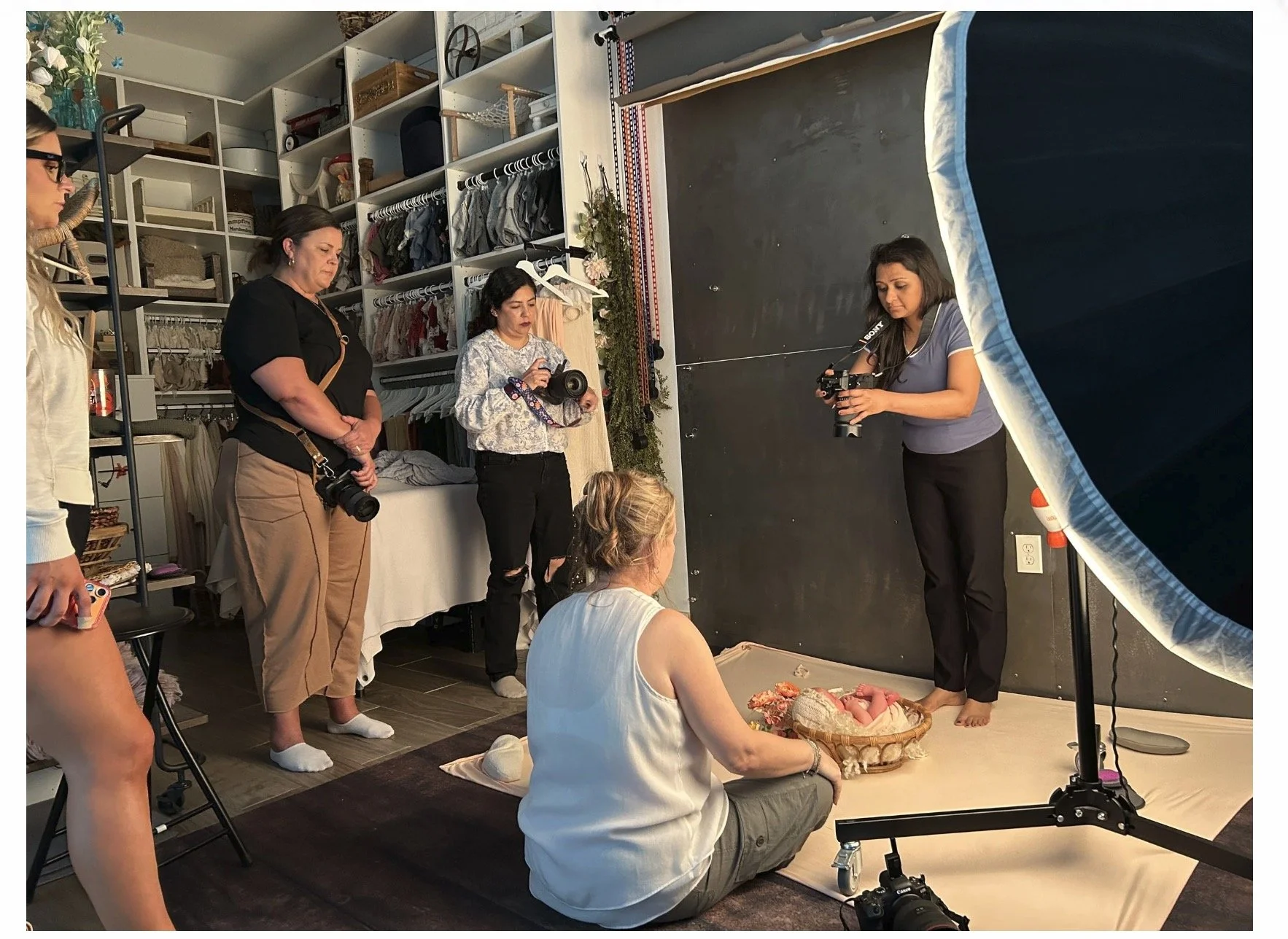 Photographers participating in a newborn photography education workshop in Austin Texas while photographing a newborn session and learning studio lighting techniques.