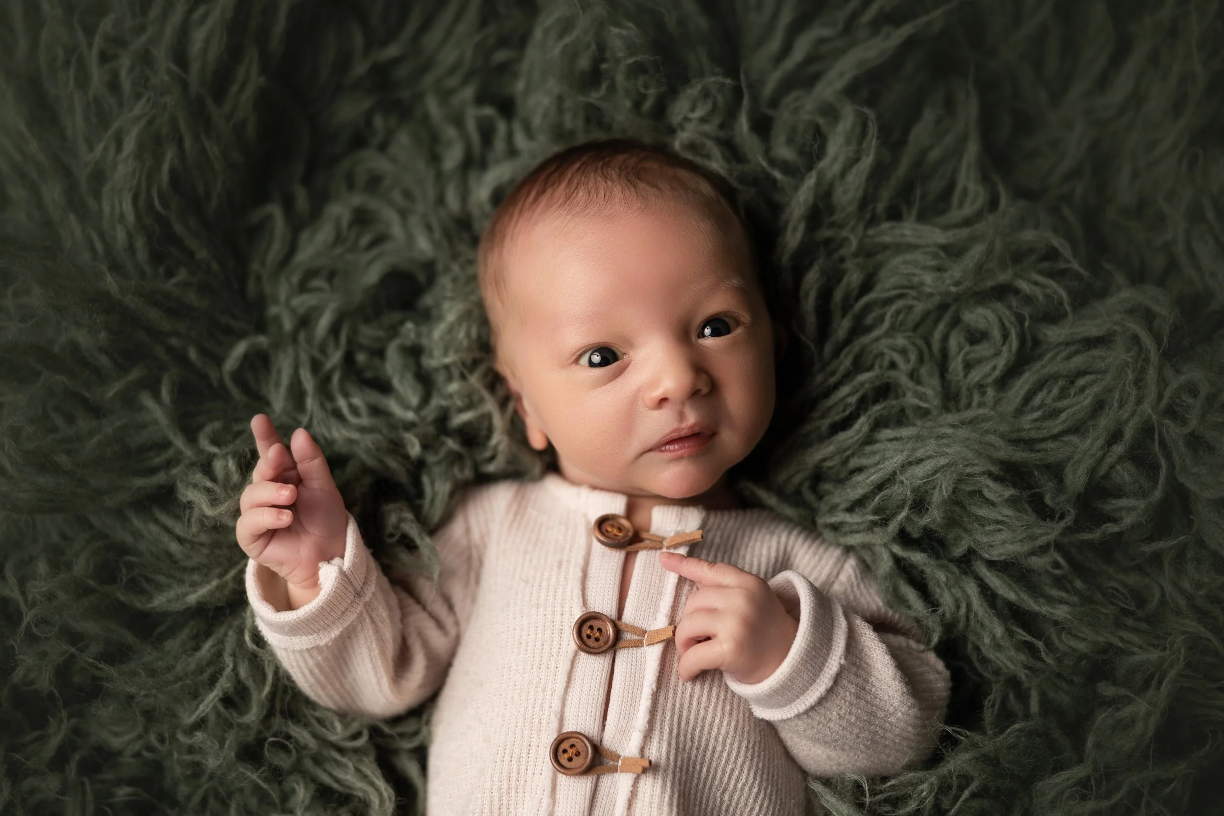 Awake newborn baby making a funny expression during a studio newborn photography session in Austin, Texas.