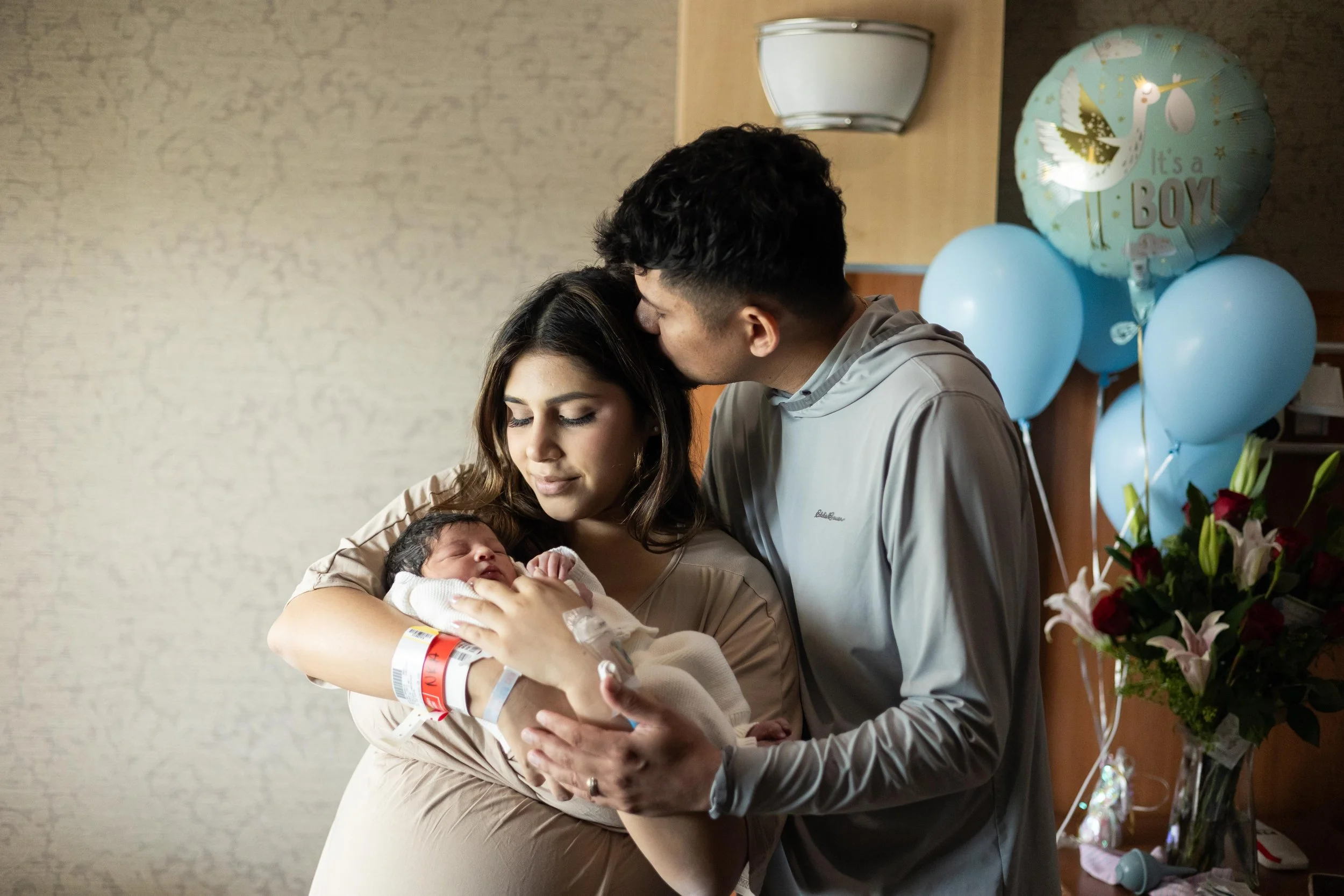 New parents cuddling their newborn baby in the hospital during a Fresh 48 newborn photography session in Austin, Texas.