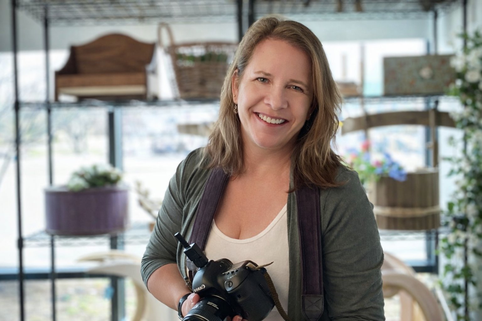 photographer in Austin Texas holding canon dslr with newborn props in the background