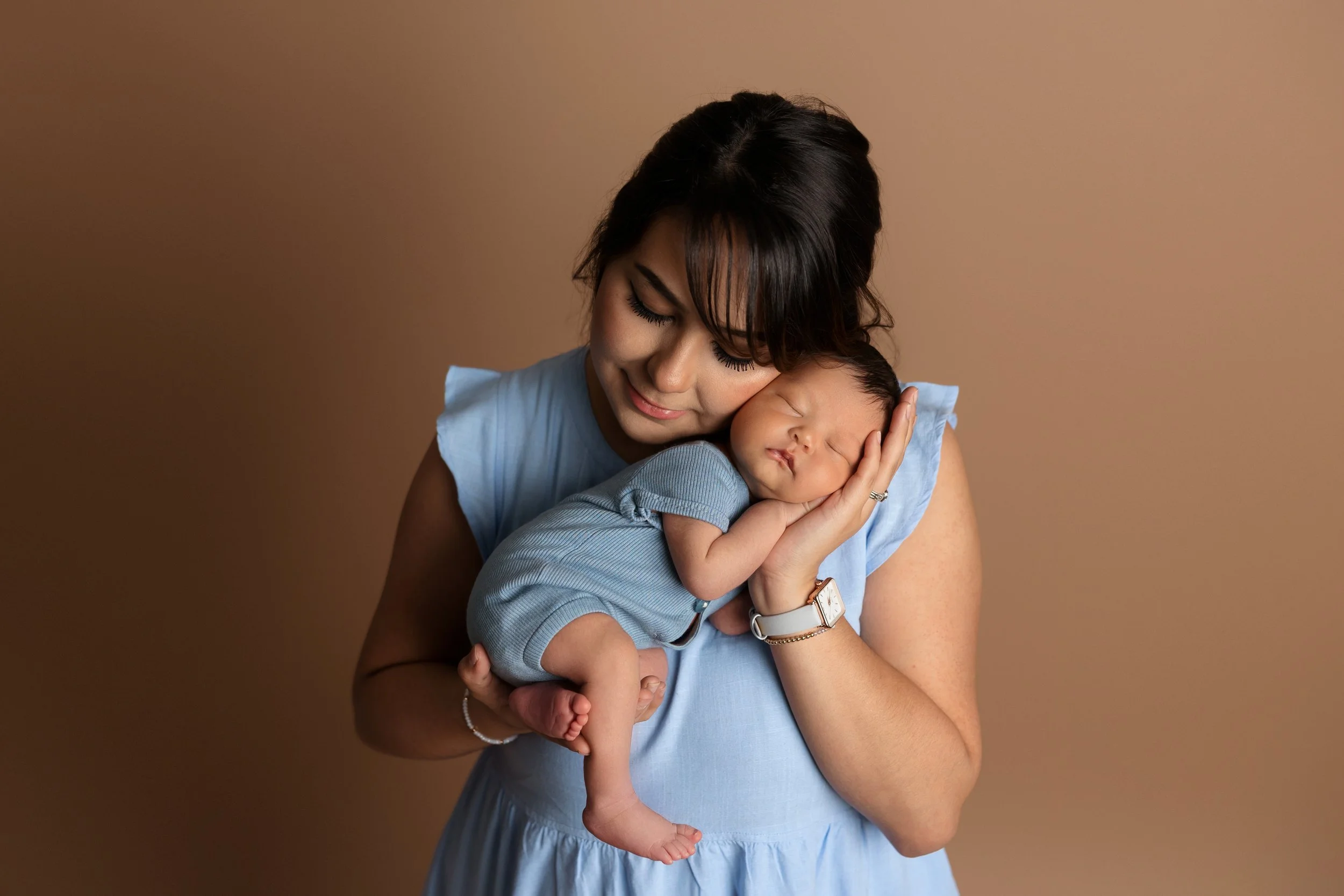 New mom cuddling her sleeping baby during a studio newborn photography session in Austin, TX.