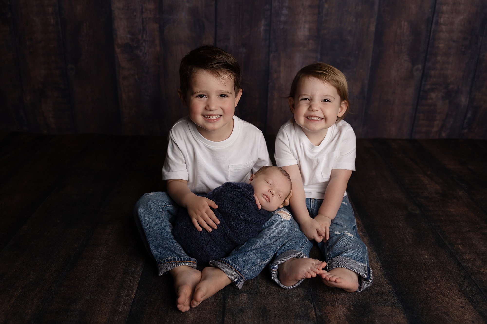 newborn baby with two bigger brothers posed in photography studio in austin Texas