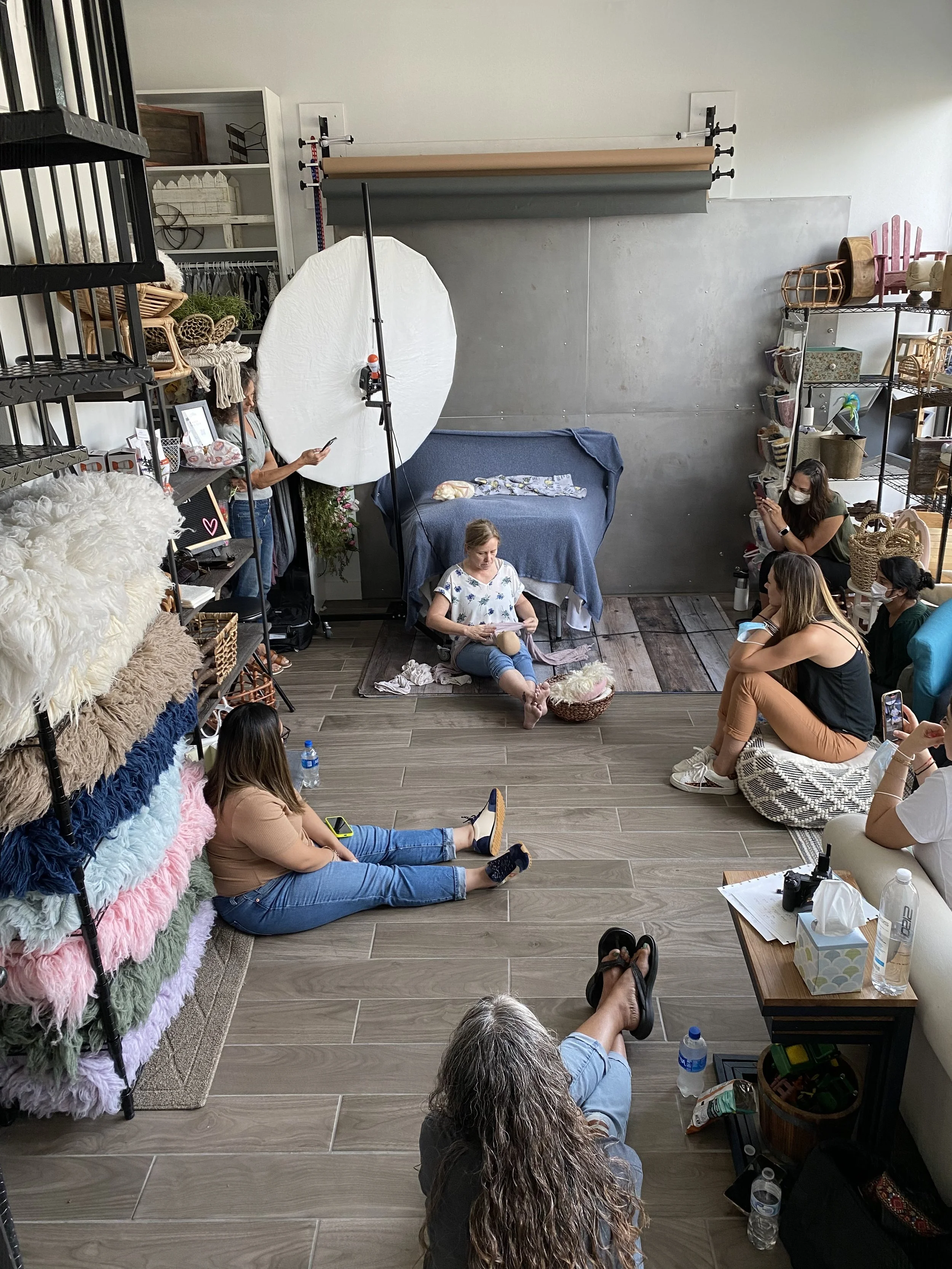Photographers attending a newborn photography workshop in an Austin studio learning newborn safety, posing, and workflow techniques.