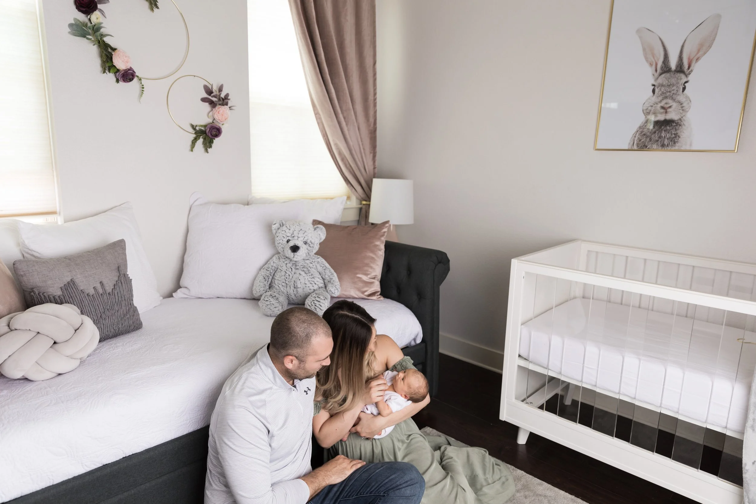 Parents cuddling their newborn in the nursery during an in-home lifestyle newborn photography session in Austin, Texas.