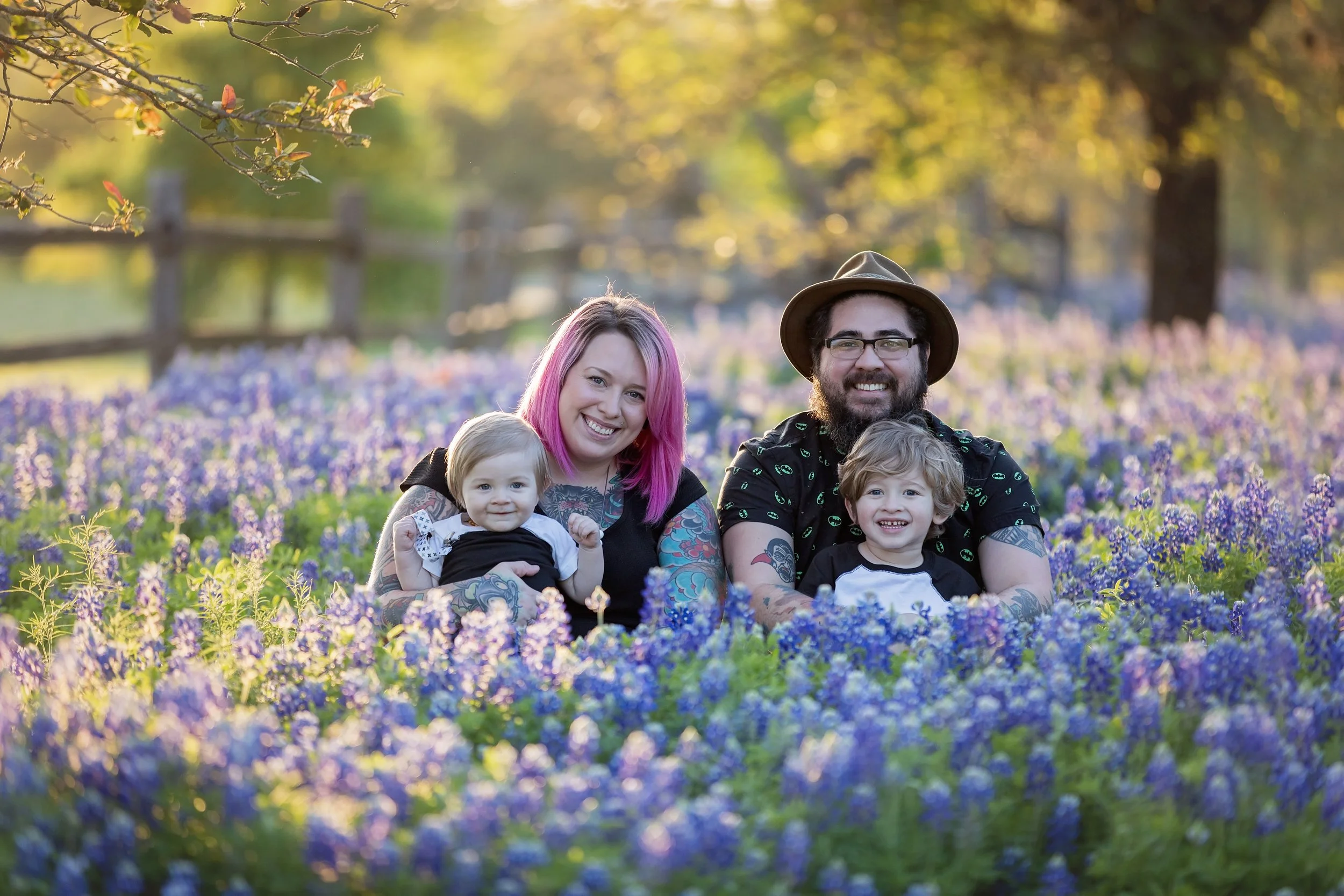 Family with two young children smiling together during a golden hour bluebonnet photography session in Austin, Texas.