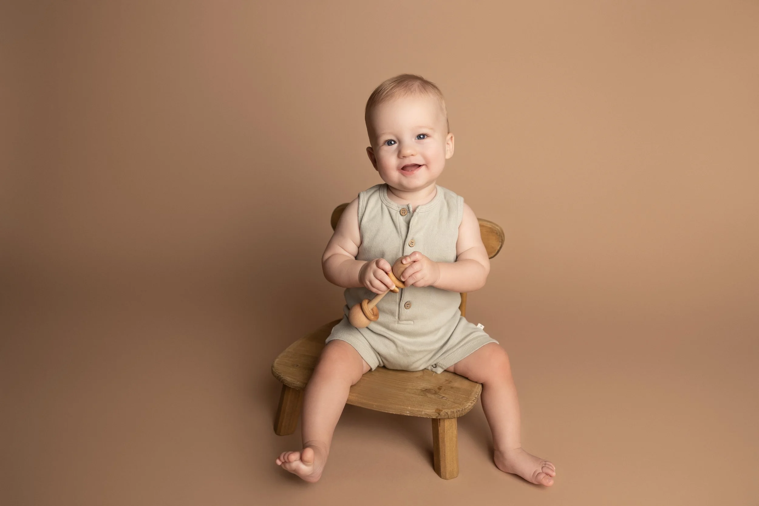Smiling baby boy sitting on a wooden chair during an Austin milestone photography session