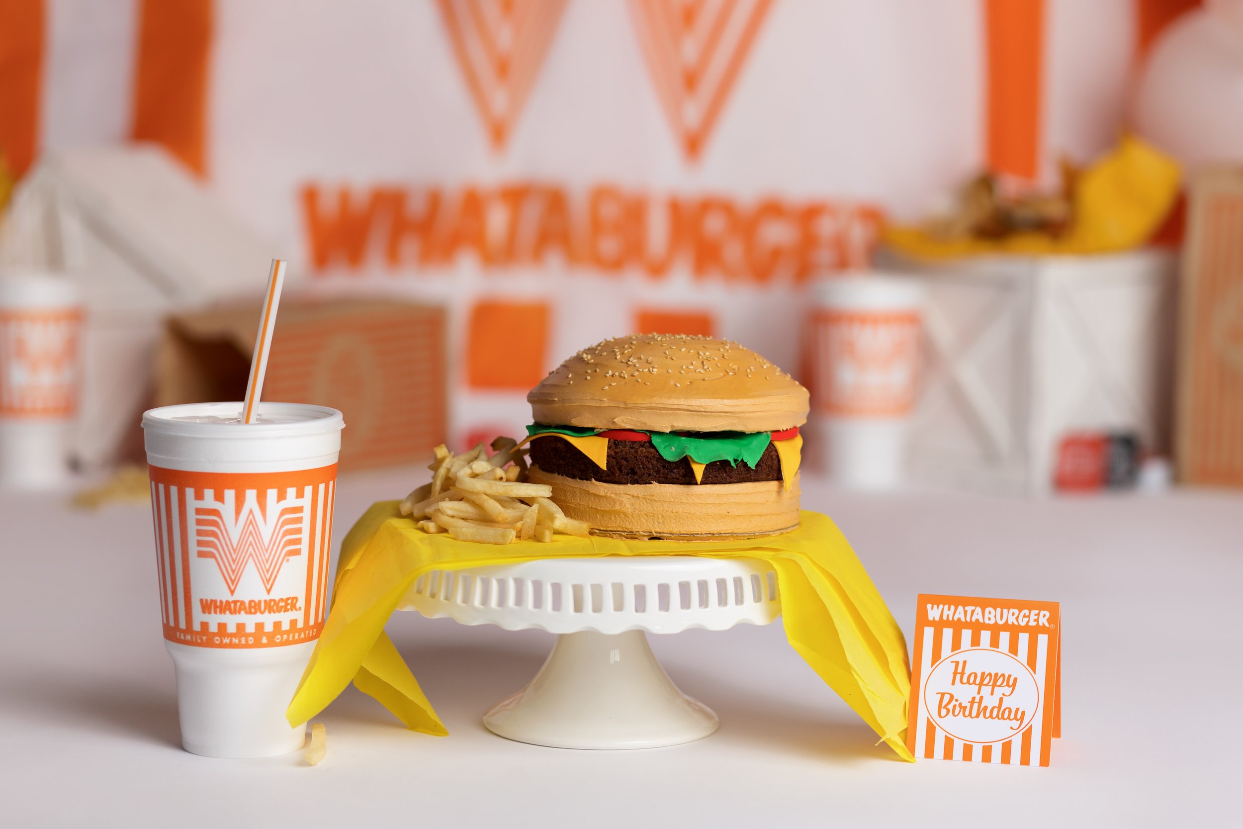 Whataburger-inspired first birthday cake smash setup with burger cake, fries, and orange themed decorations in Austin TX.