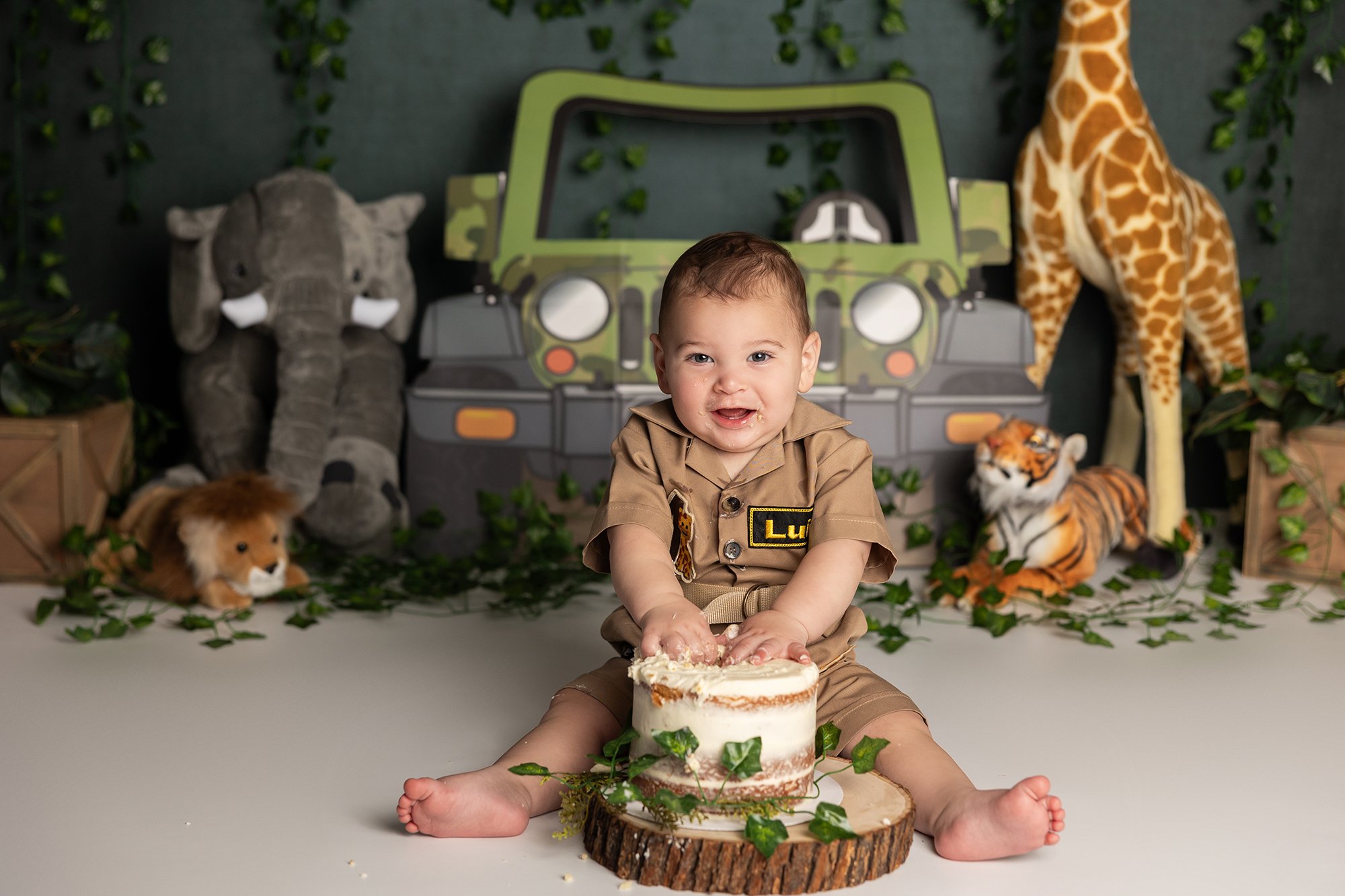 Simple safari themed cake smash setup with baby smiling during first birthday session in Austin TX