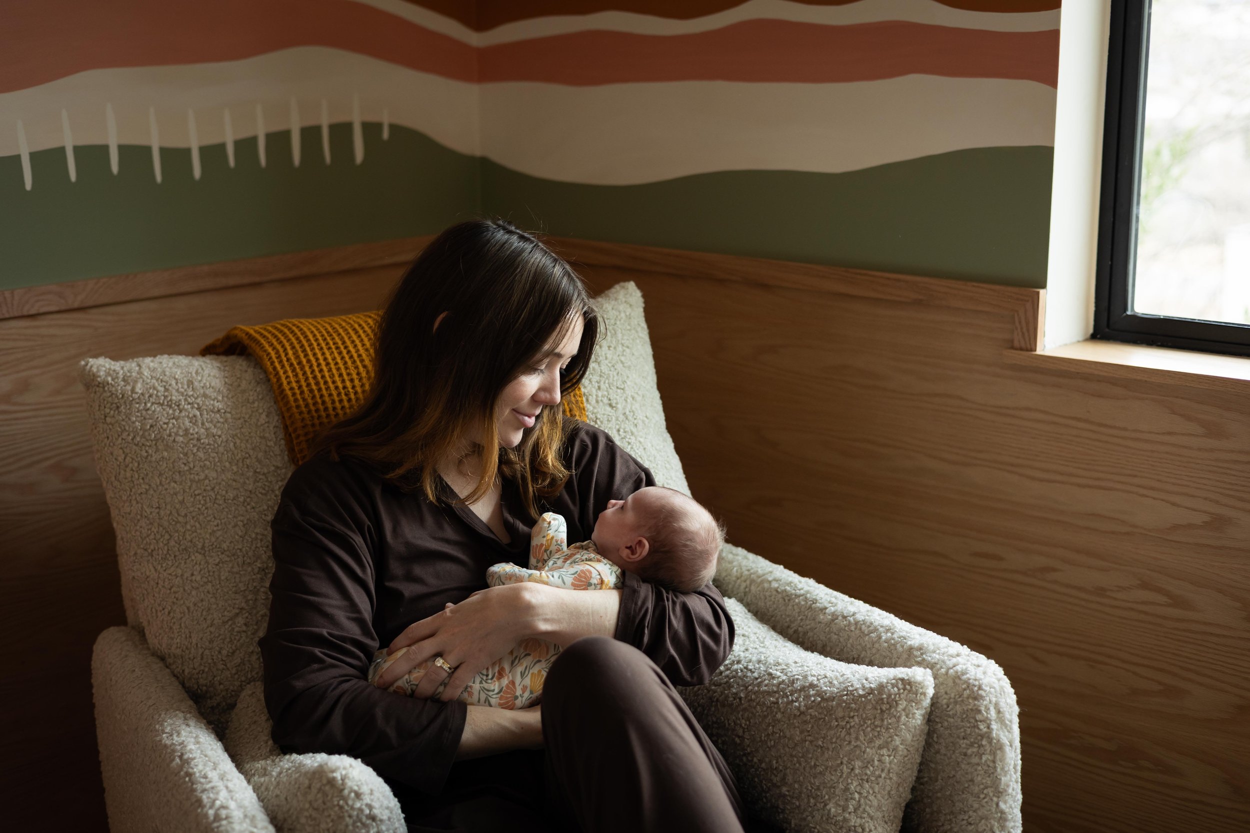 Austin lifestyle newborn photography session with a mother holding her newborn baby in a nursery at home in Austin, Texas.