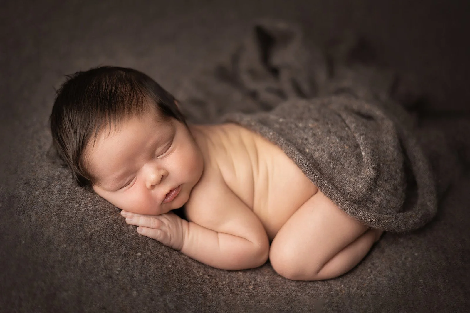 Sleeping newborn safely posed on a beanbag during a professional newborn photography session in Austin, TX.