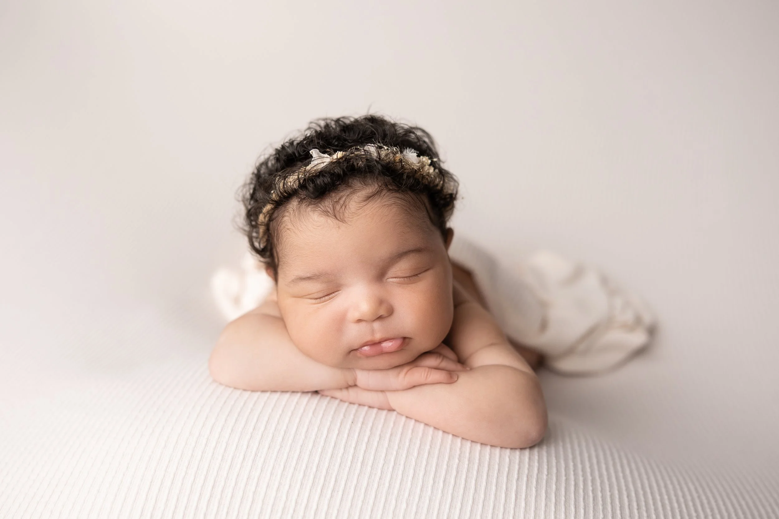 newborn baby resting chin on hands pose on neutral beanbag backdrop