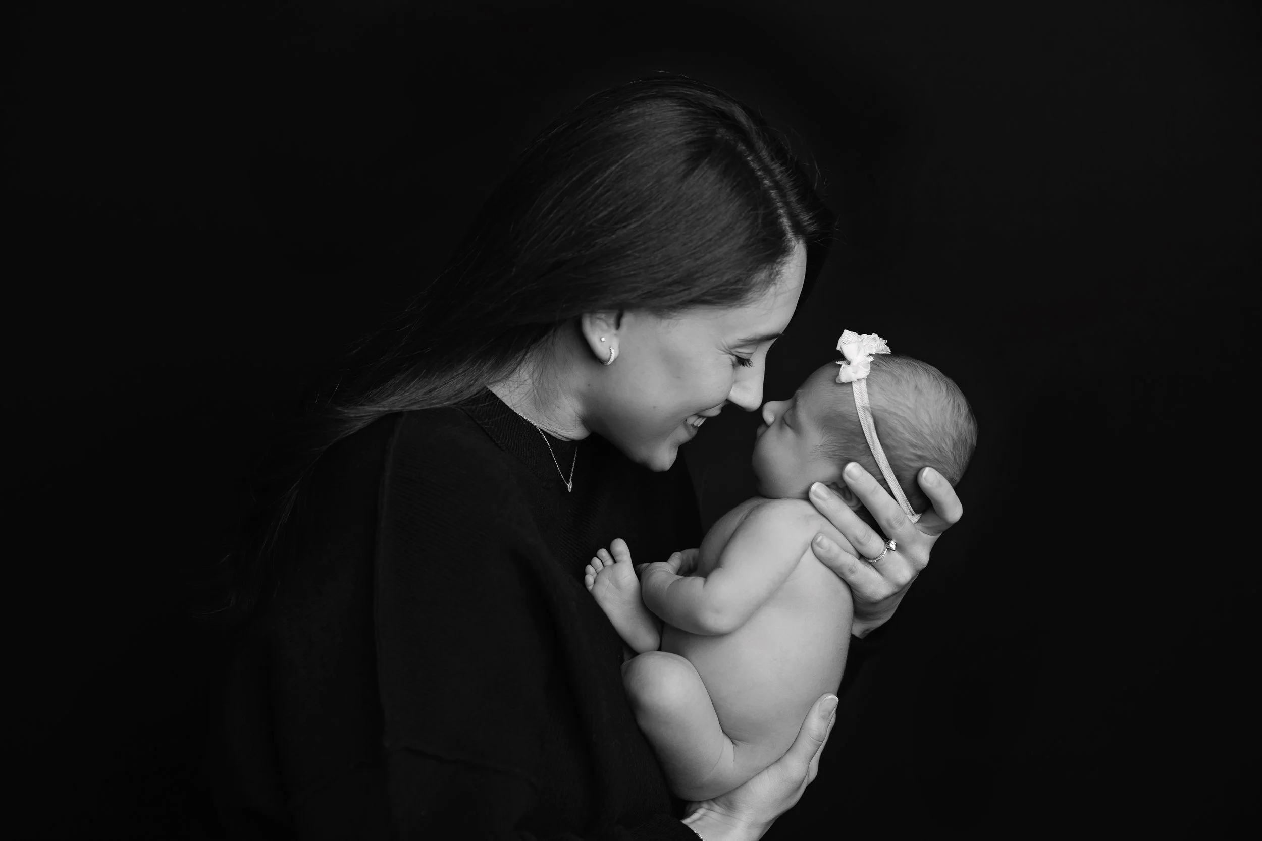 Black and white portrait of mother holding newborn baby close to her face