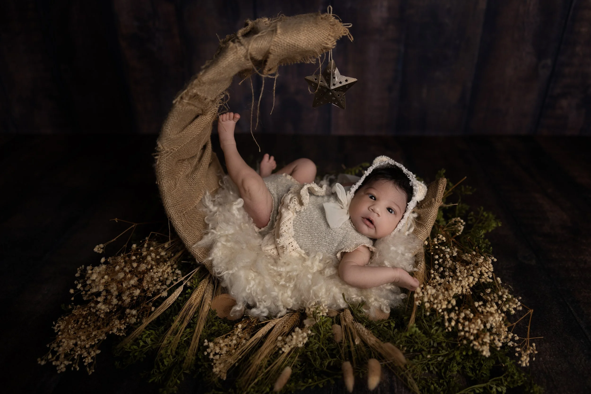 Awake newborn baby photographed in a moon prop during a studio newborn session in Austin, Texas.