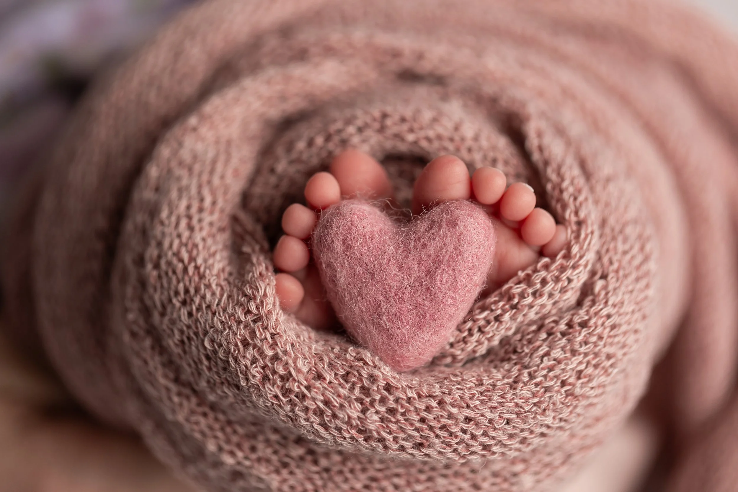 baby girl's toes around soft pink heart