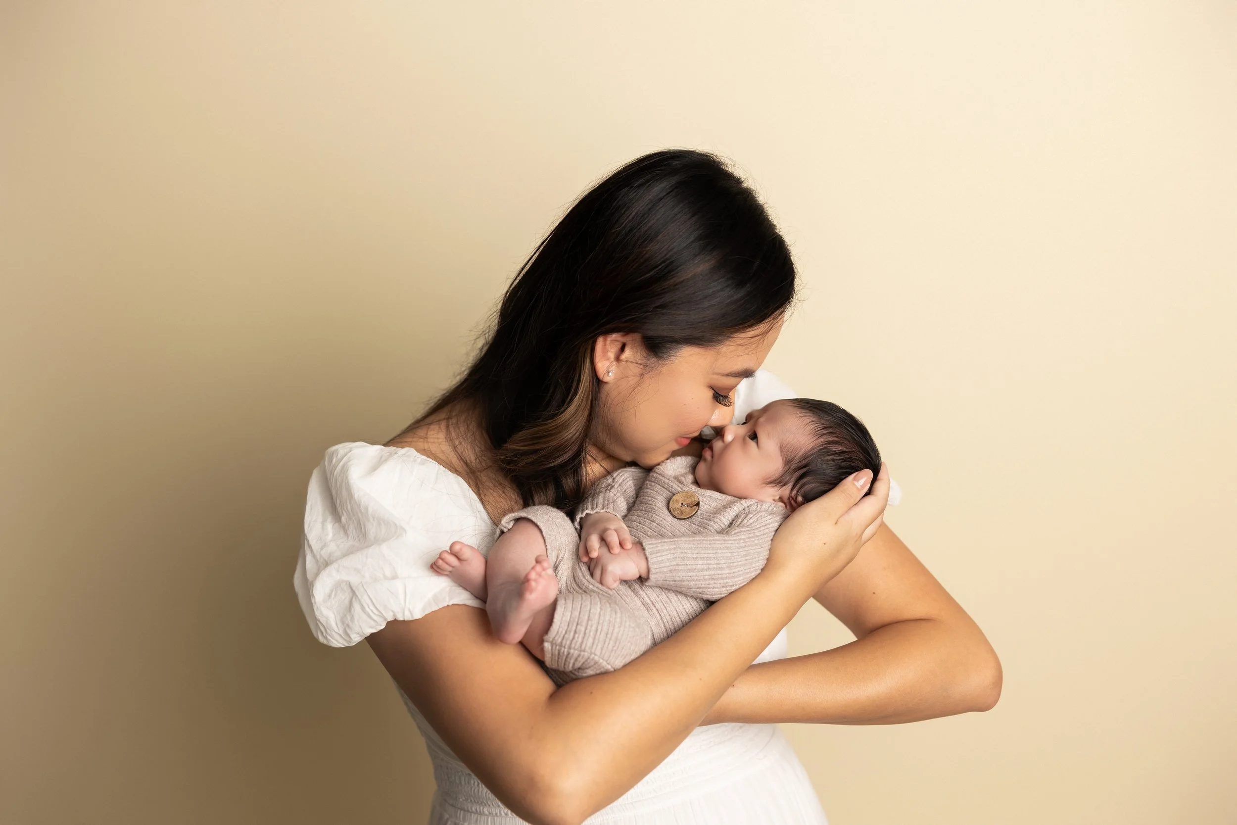 Mother holding sleeping newborn during a soft neutral studio newborn session