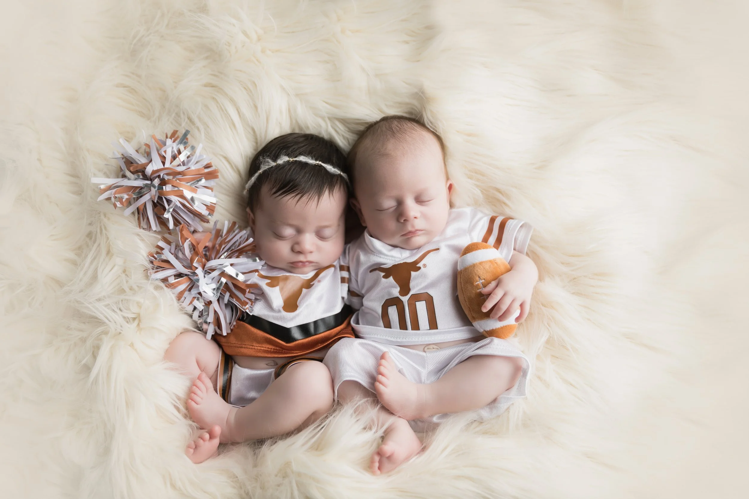 boy and girl newborn twins wearing longhorns football and cheerleader outfit in Austin Texas photography studio