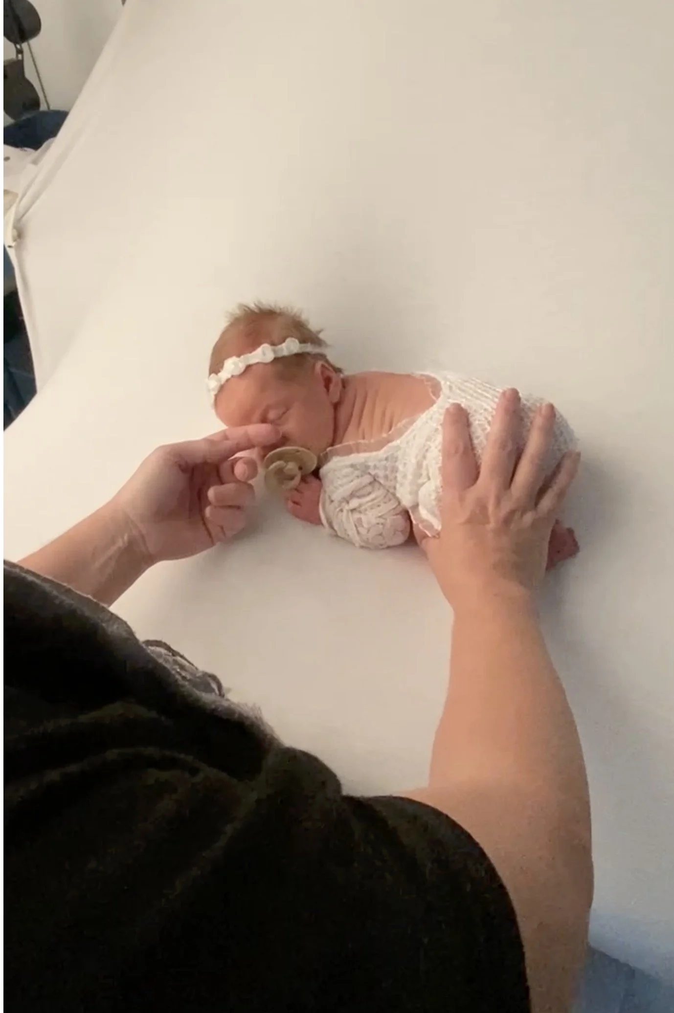 Austin newborn photographer using gentle swiping motion between baby’s eyes to encourage sleep during newborn session