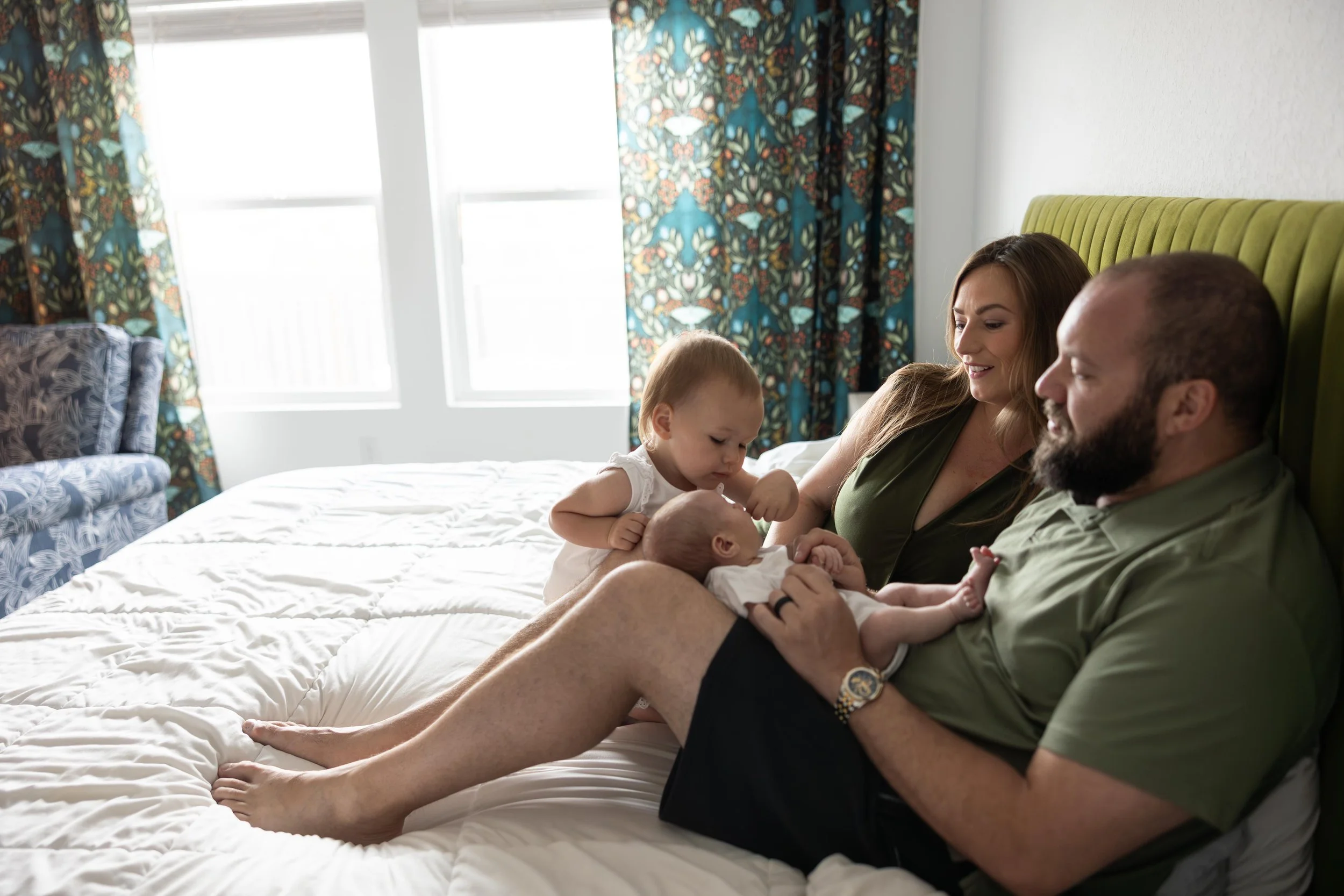Family cuddling with a newborn and toddler during an in-home newborn photography session in Austin, Texas.