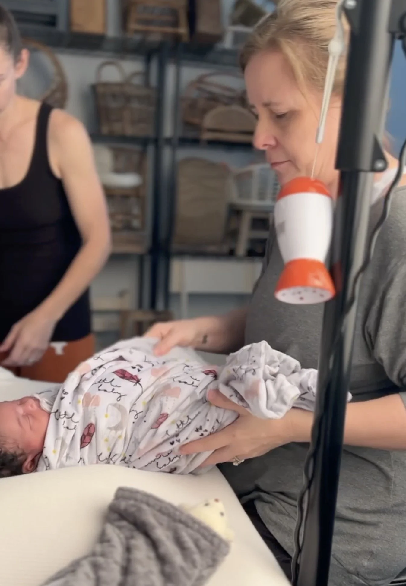 Austin newborn photographer using white noise shusher and swaddling techniques to soothe baby during photography session
