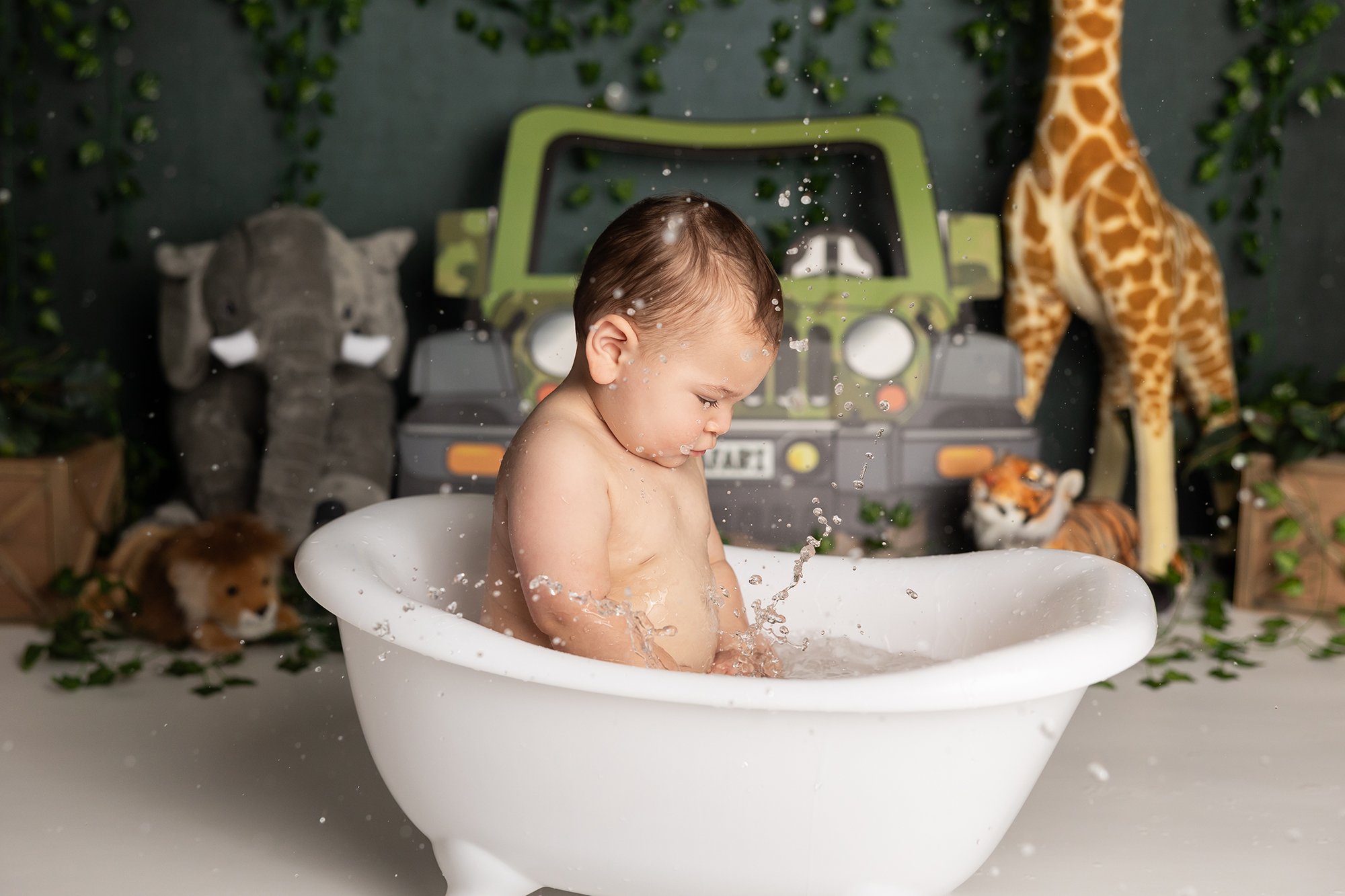 Baby splashing in tub after cake smash session in Austin TX