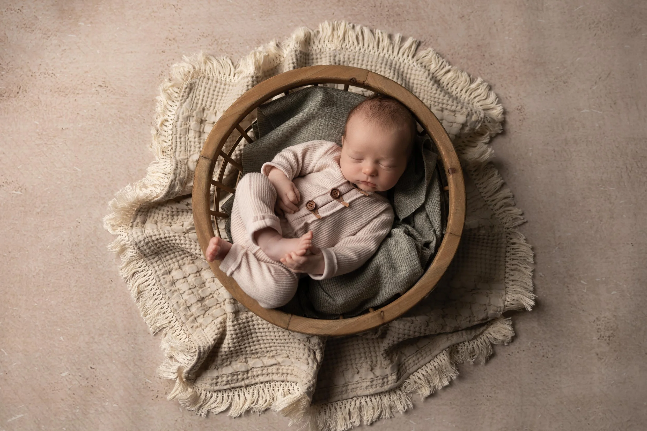 Newborn baby boy in huck finn pose within round basket prop at Jessica Doffing Photography in Austin Texas