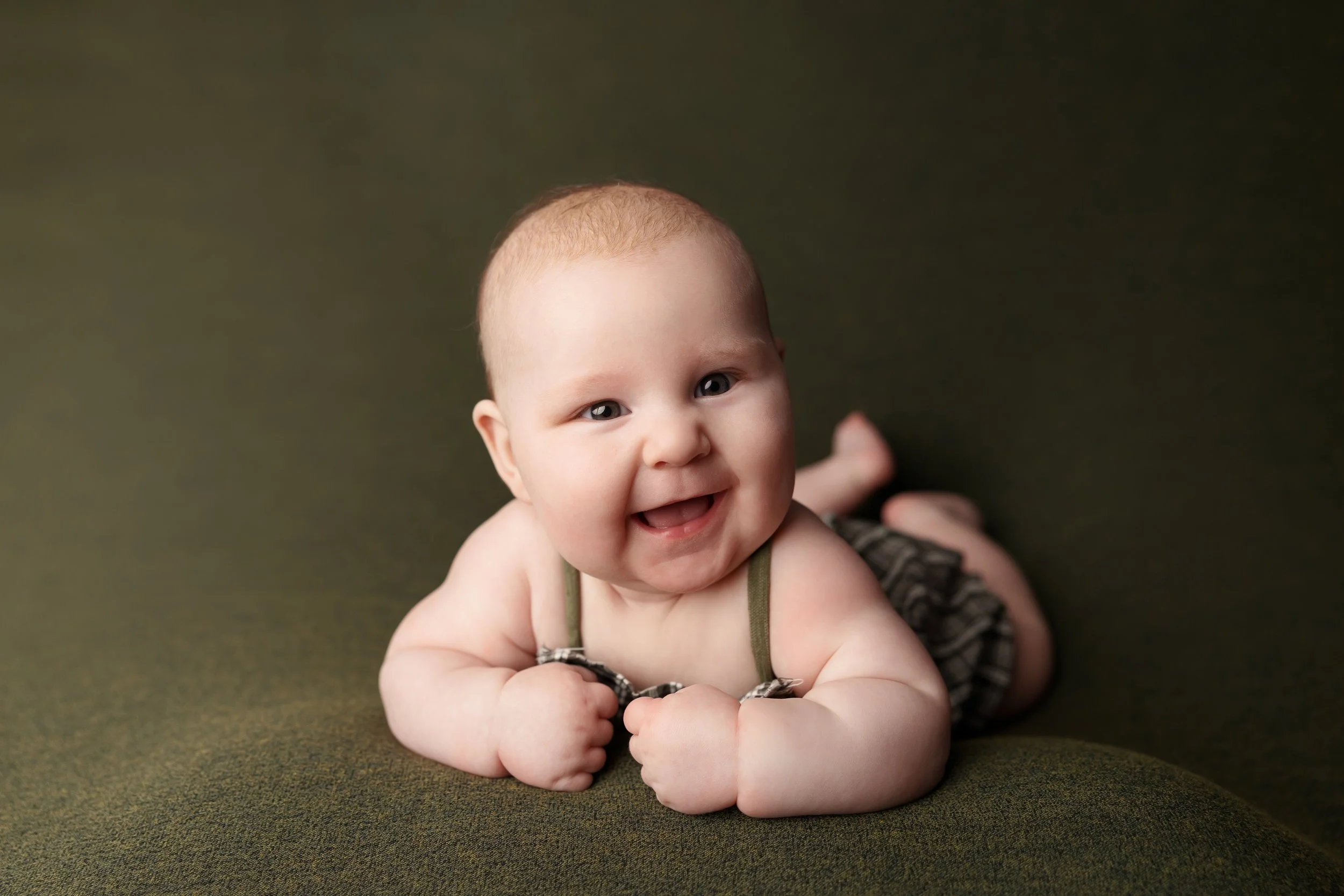 Three-month-old baby smiling during a tummy time milestone photography session in Austin TX.