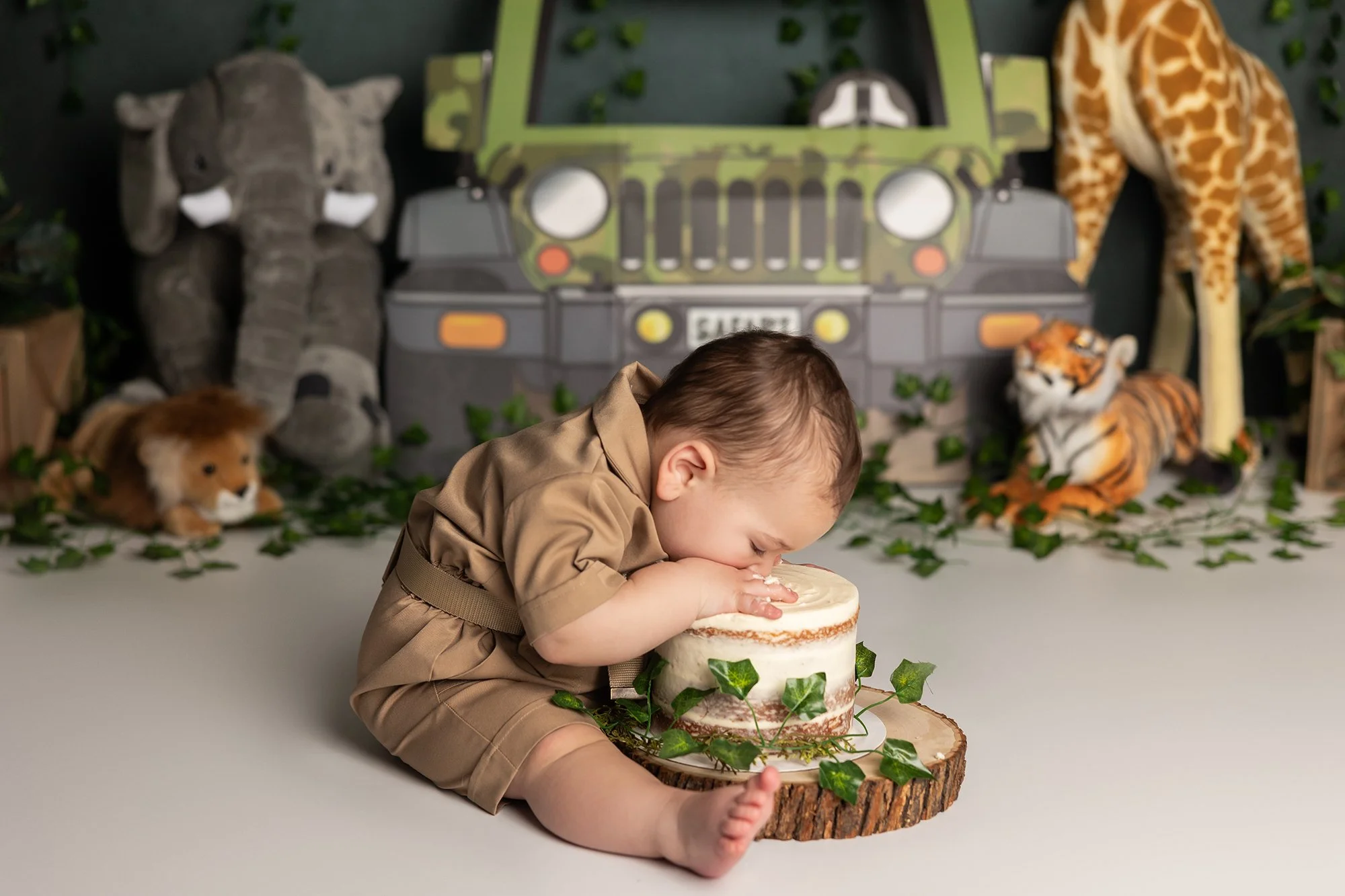 Baby face in cake during first birthday safari cake smash session in Austin TX