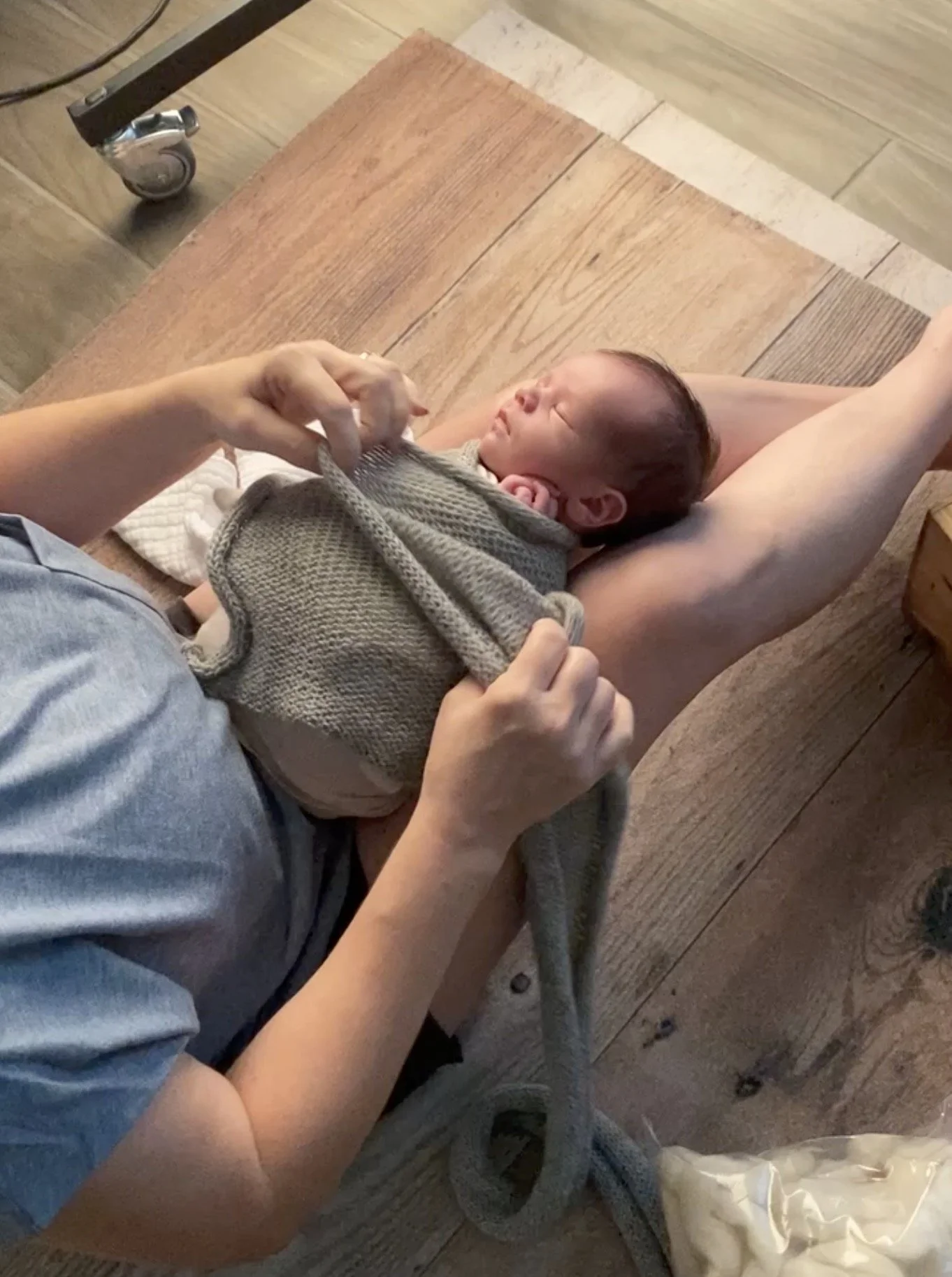 Austin newborn photographer gently swaddling newborn baby during studio session to help soothe and settle baby to sleep