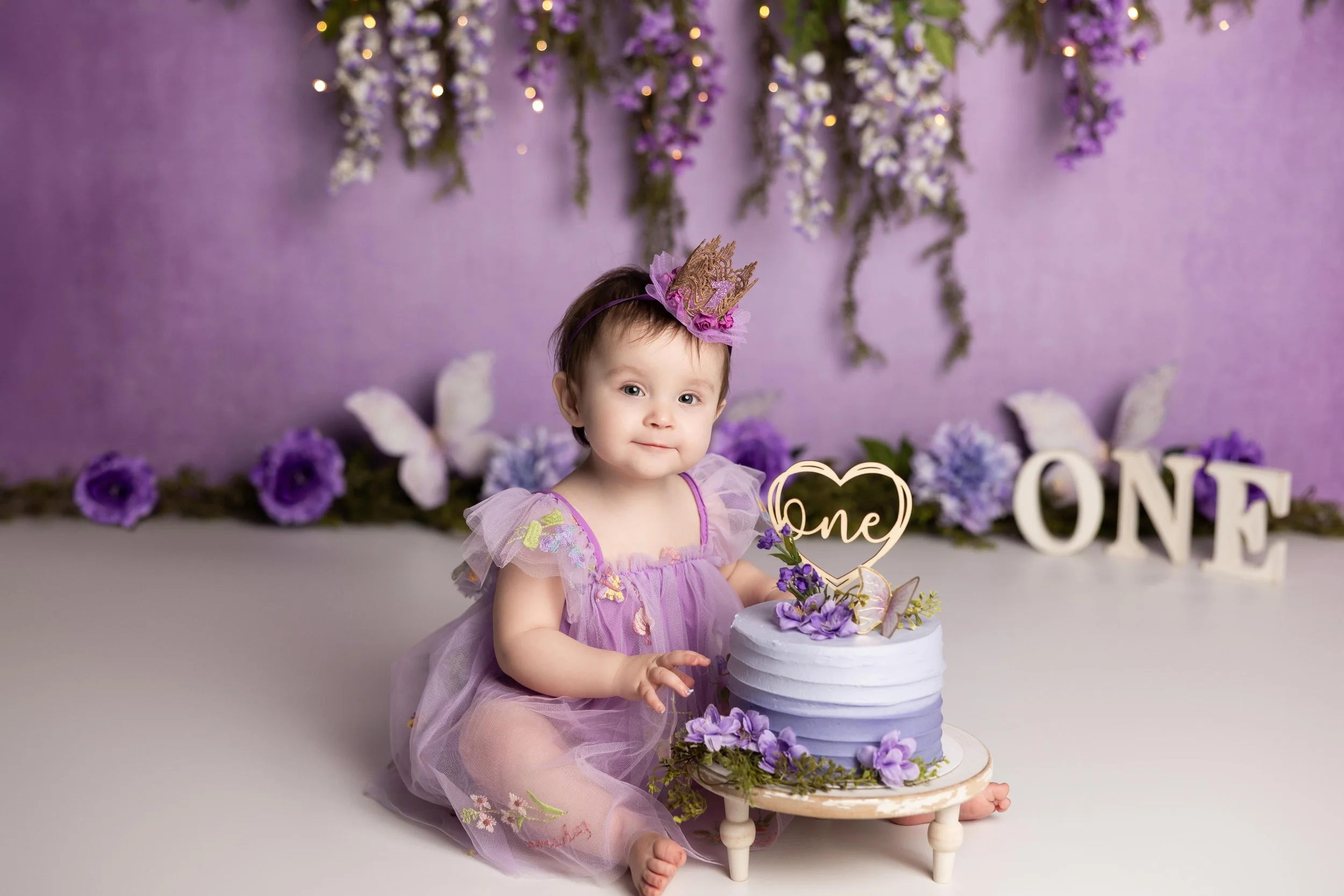 First birthday cake smash session with purple floral theme photographed by an Austin cake smash photographer.