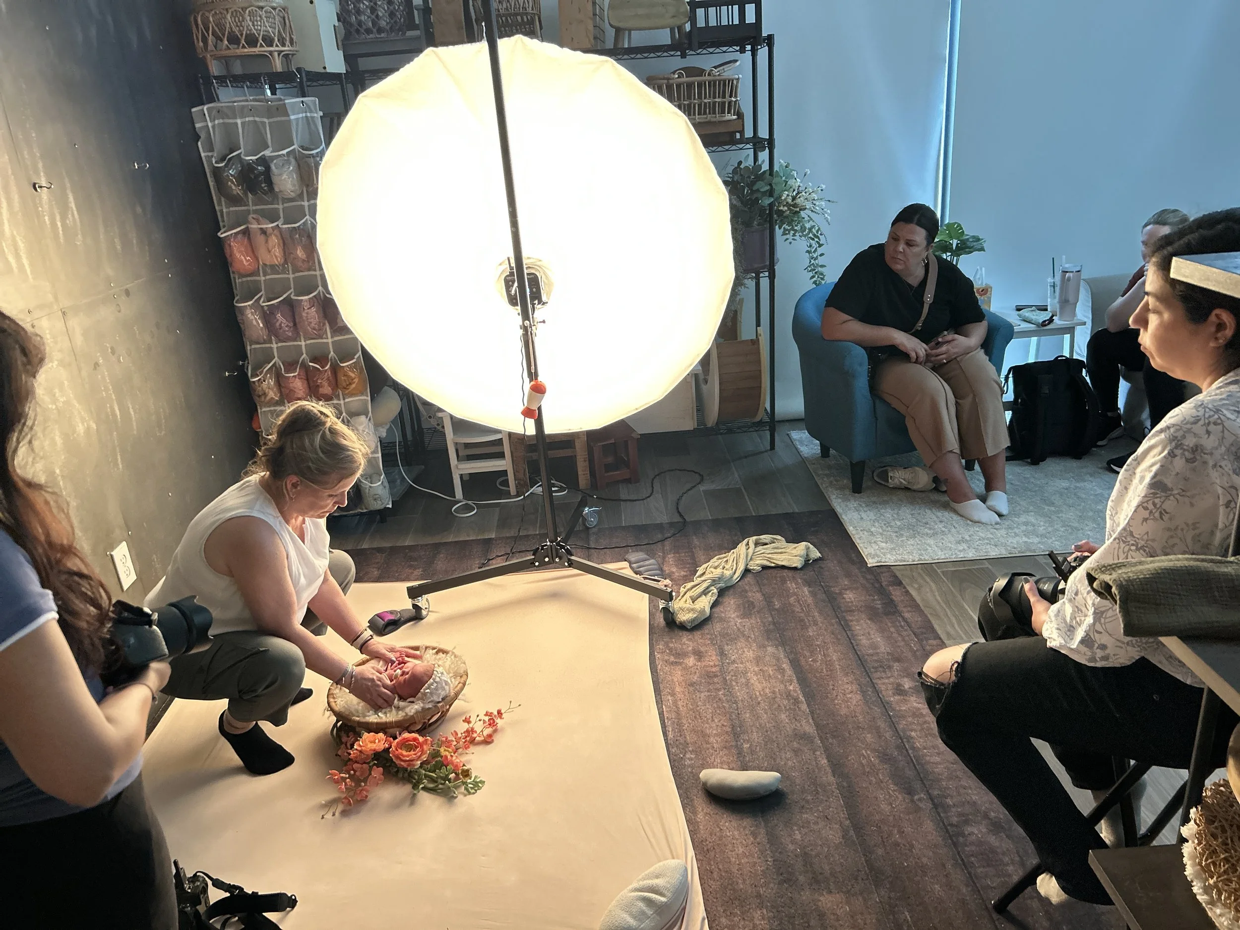 Newborn photography workshop in Austin TX with photographers observing a live newborn posing and lighting demonstration in a professional studio.