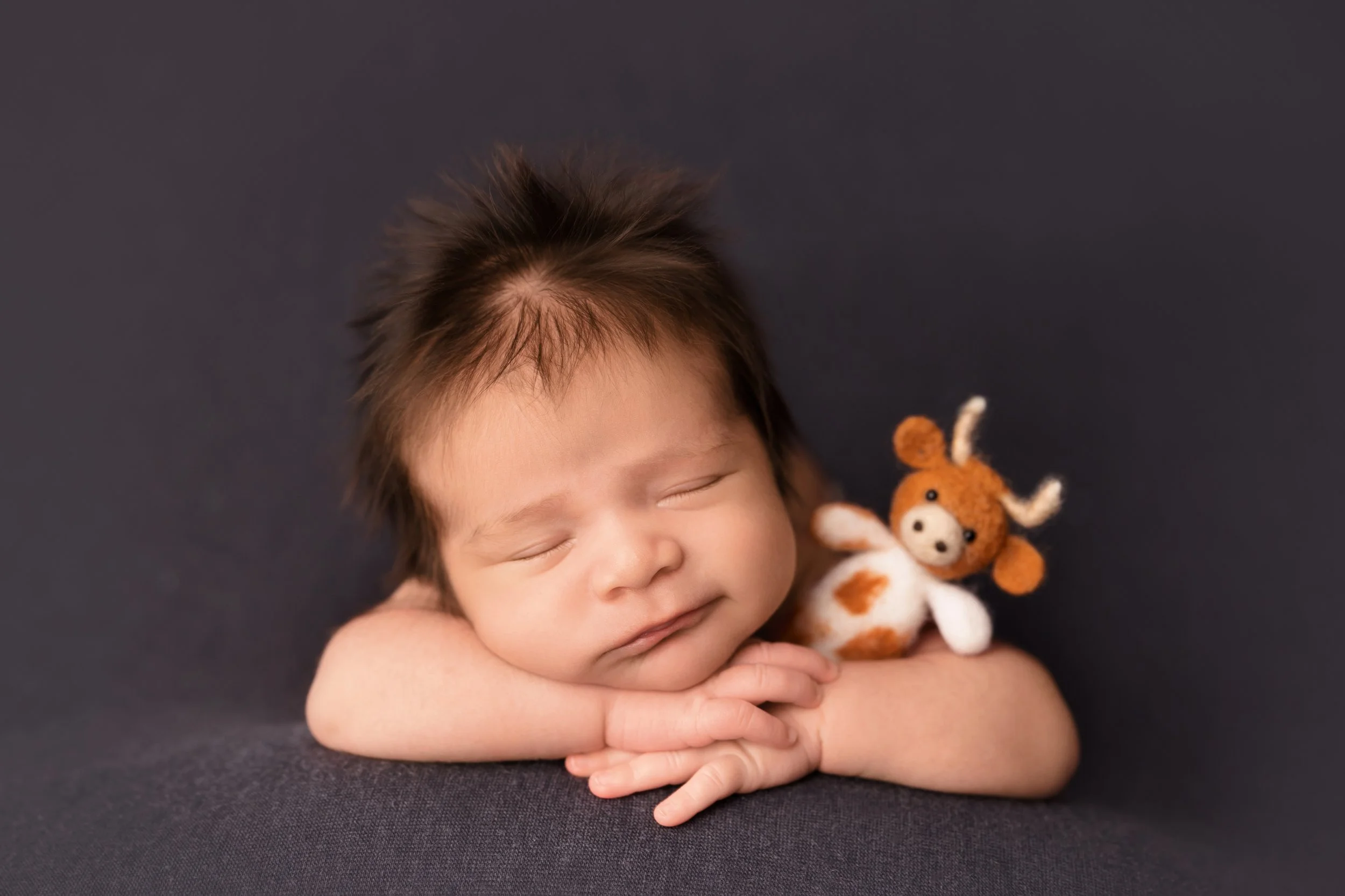 A peacefully sleeping newborn poses with a Longhorn lovie, adding a personal touch to this Austin newborn photography session.