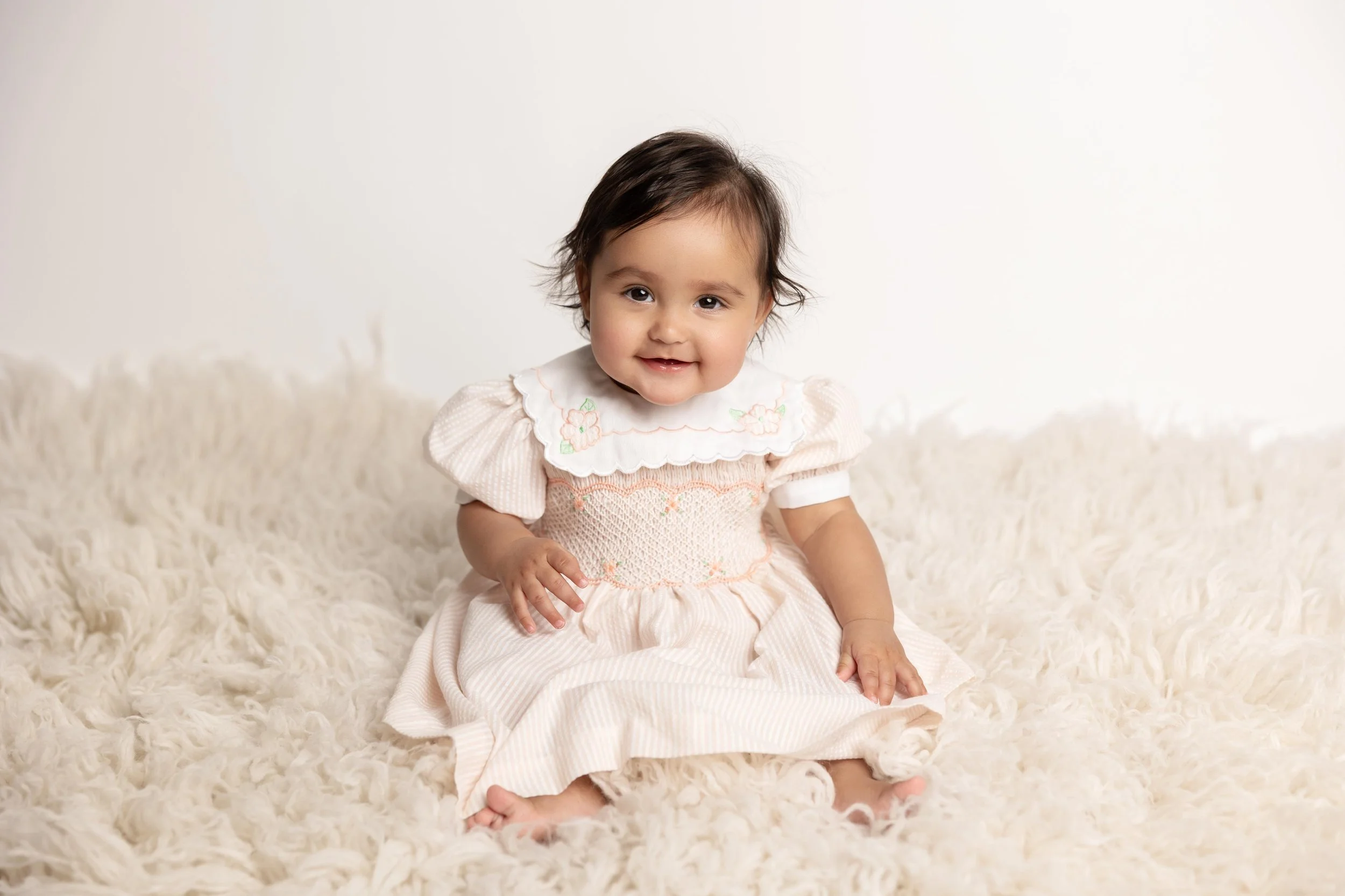 Baby girl wearing a special heirloom-style dress during her sitter milestone photos