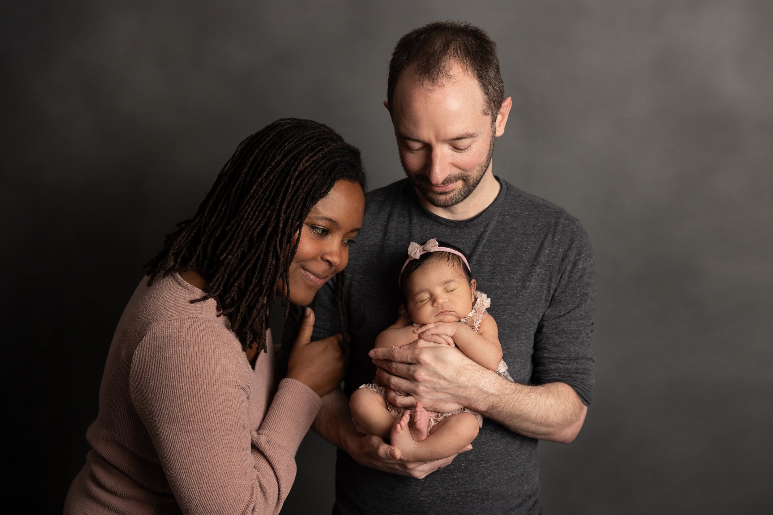Parents admiring their sleeping newborn baby during a family newborn photography session at Jessica Doffing Photography in Austin, Texas.