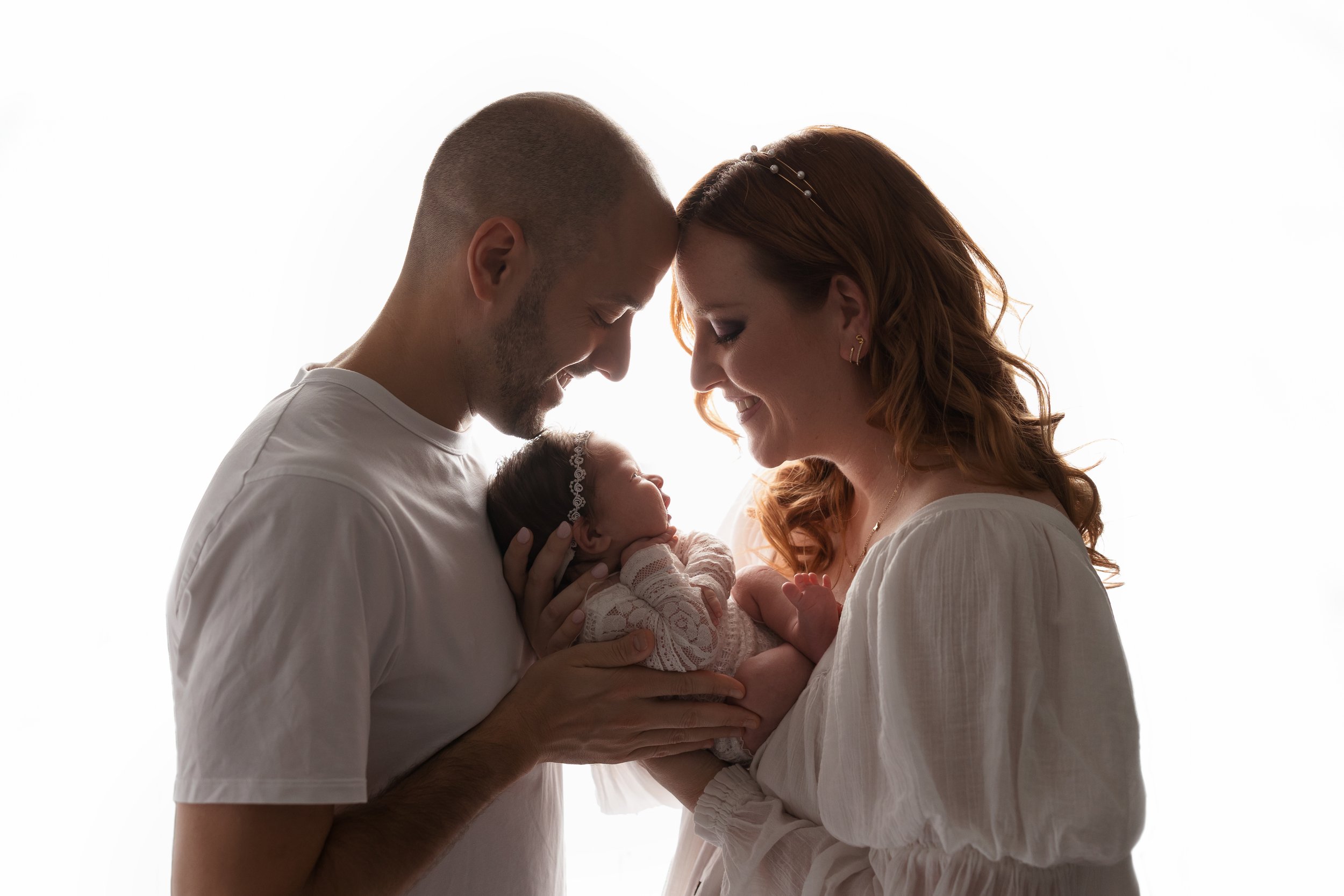 Parents smiling at their newborn during a family studio newborn photography session in Austin, TX.