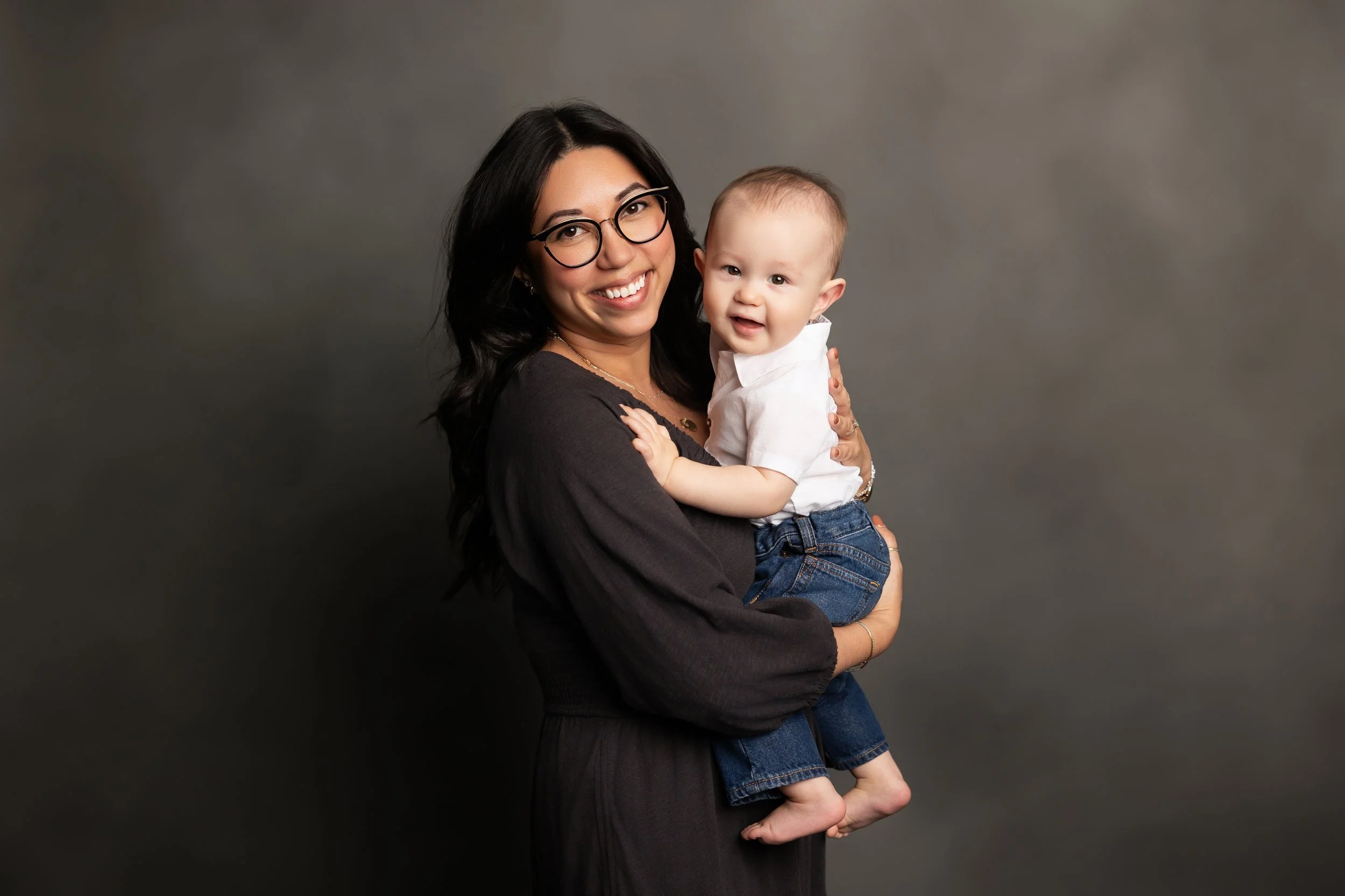 Mother holding smiling baby during a classic studio portrait session