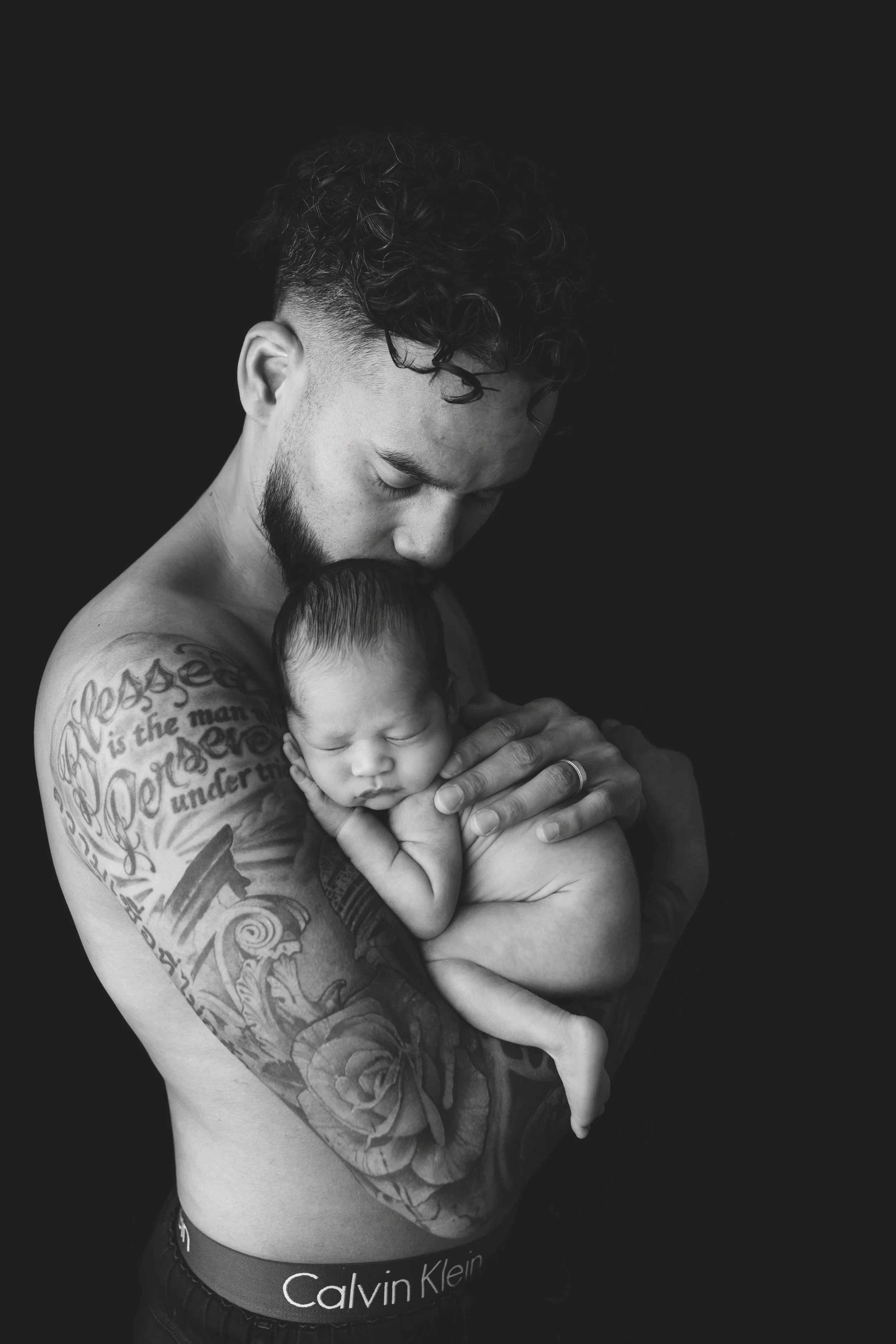 A newborn baby peacefully sleeps in dad's arms during a studio newborn photography session in Austin, Texas.