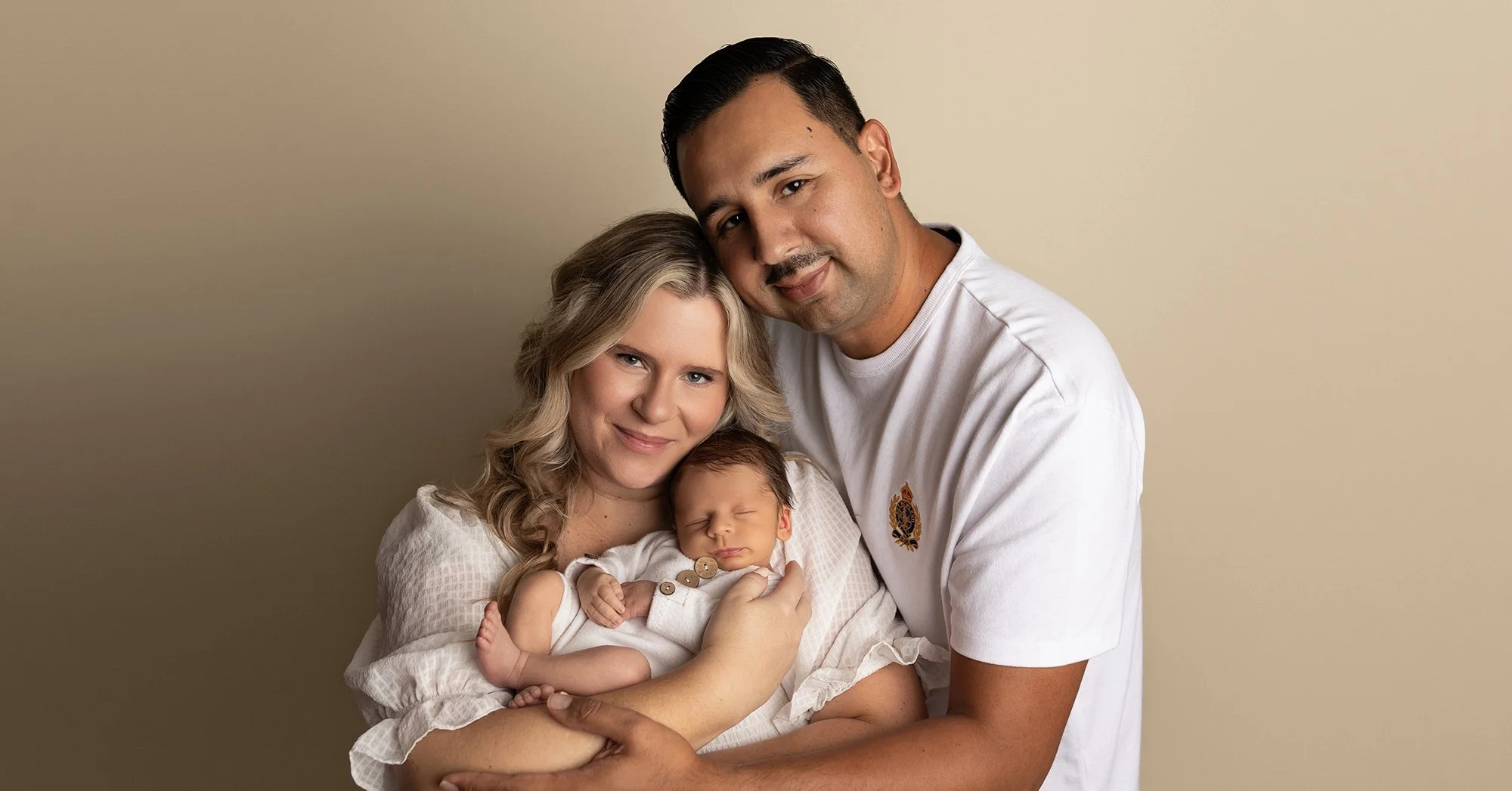 smiling parents holding newborn baby in austin photography studio