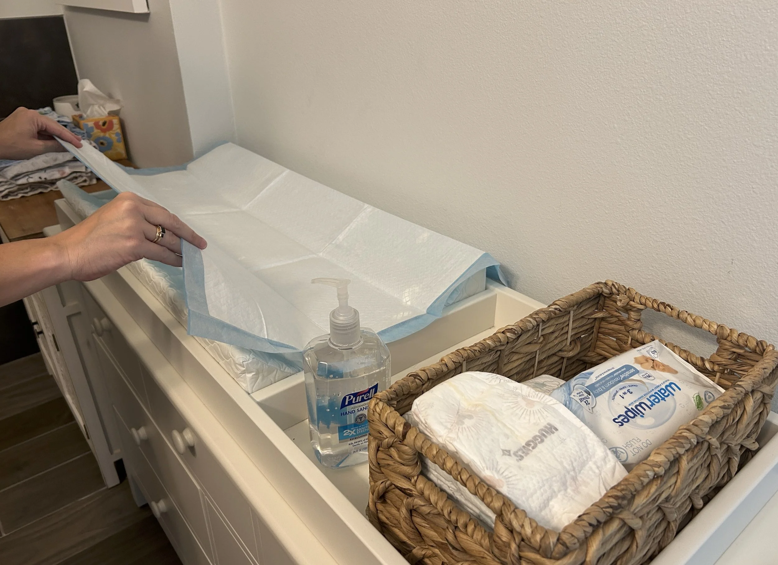 Clean newborn photography studio changing station with disposable changing pad, diapers, wipes, hand sanitizer, and baby essentials prepared before a newborn photography session in Austin, TX.