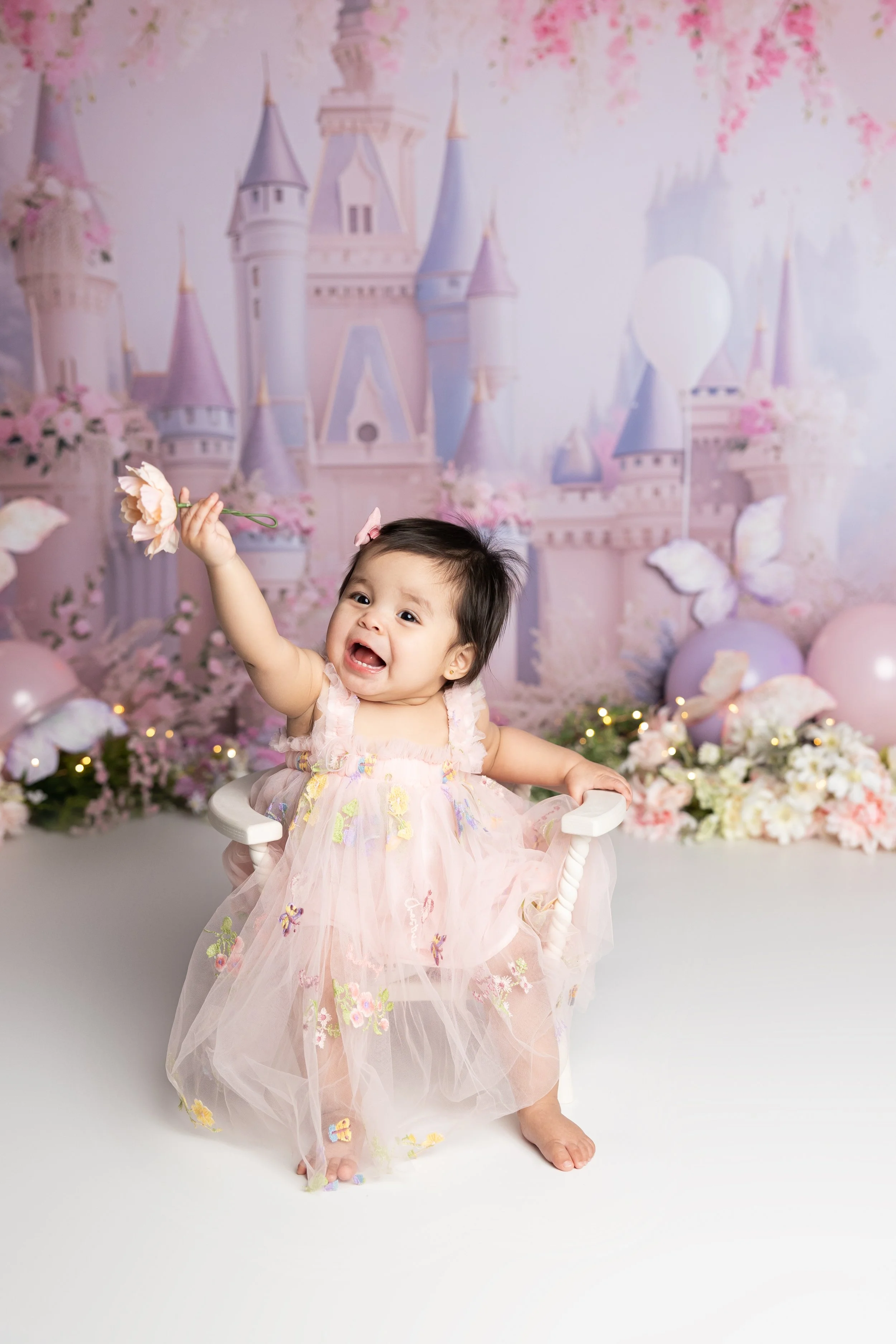 Princess-inspired first birthday portrait session featuring a whimsical castle backdrop and soft pastel styling.