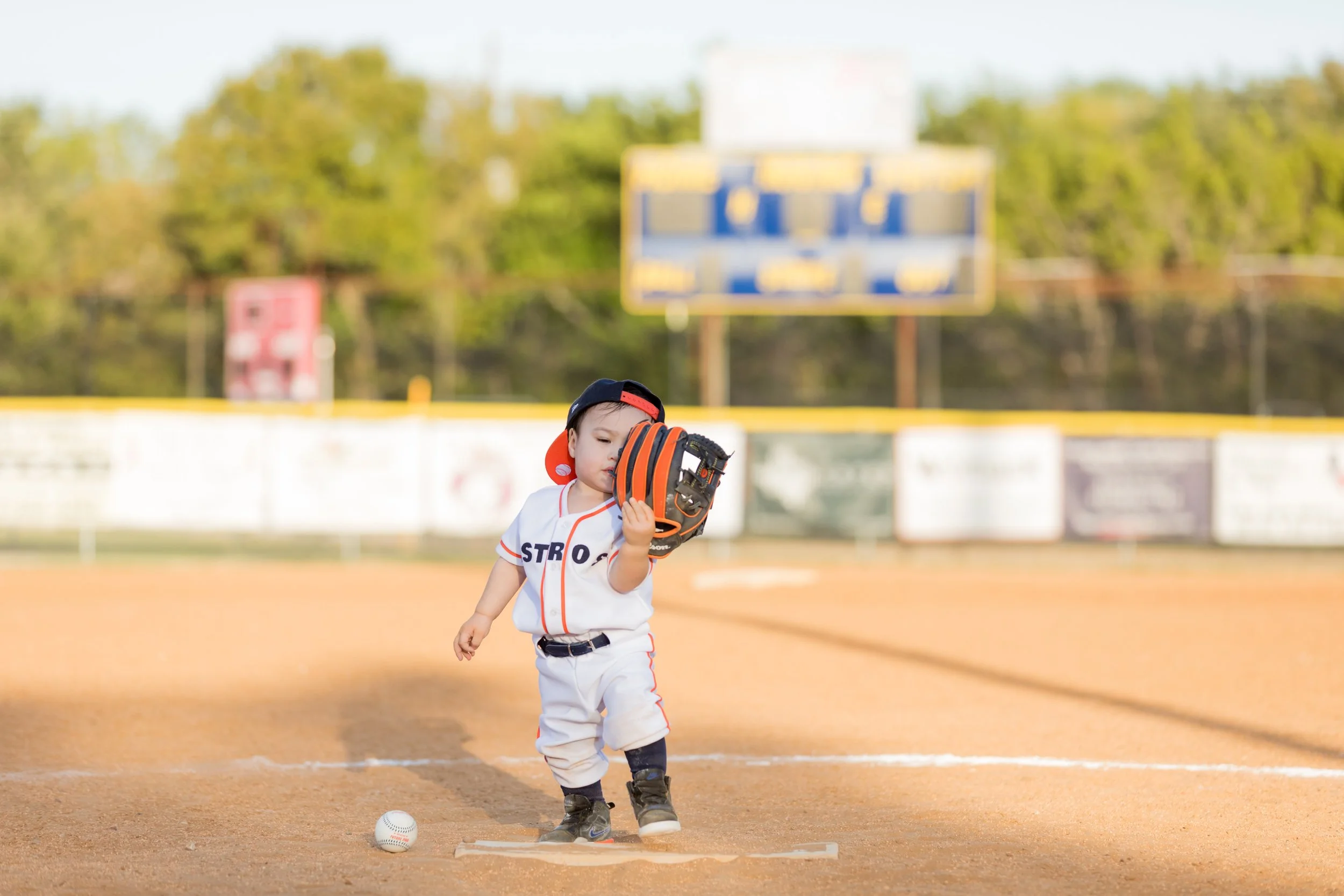 toddler playing on baseball field for birthday photo session in Austin TX