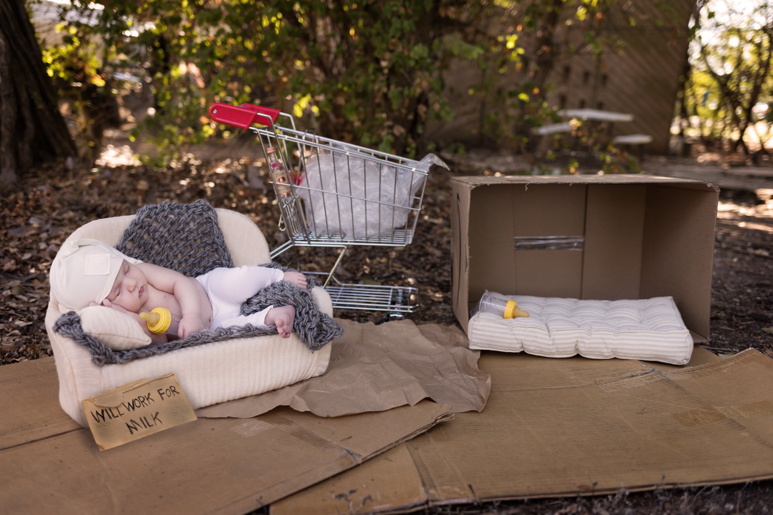 Humorous Zoolander-inspired newborn photo featuring a miniature shopping cart and creative storytelling elements.