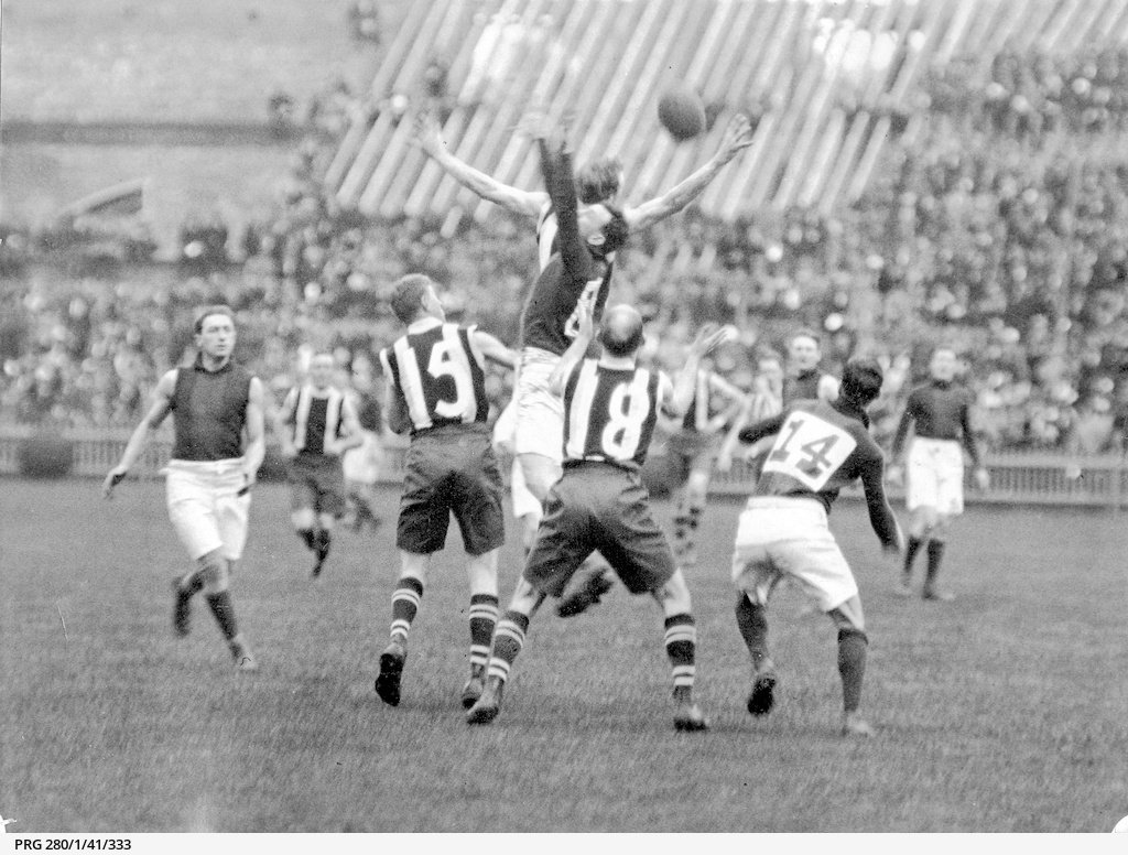 Players jumping for the ball during a football match between the South Australian Second Eighteen (striped guernsey)and Tasmania at the Adelaide Oval held at the Adelaide Oval 21st July 1923