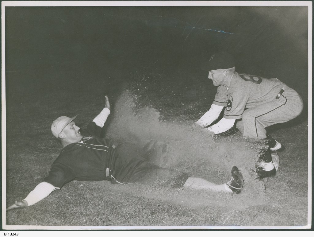 Action shot of two players at a night baseball match at Norwood Oval, held on three nights, December 29th, 30th and 31st 1952, South Australia versus Victoria