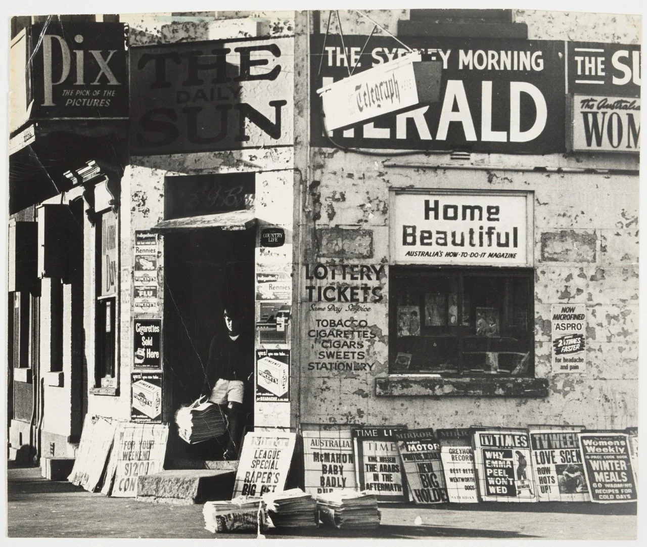 Corner newsagency of E.G. Berry with paperboy and newspaper and magazine posters, 1967