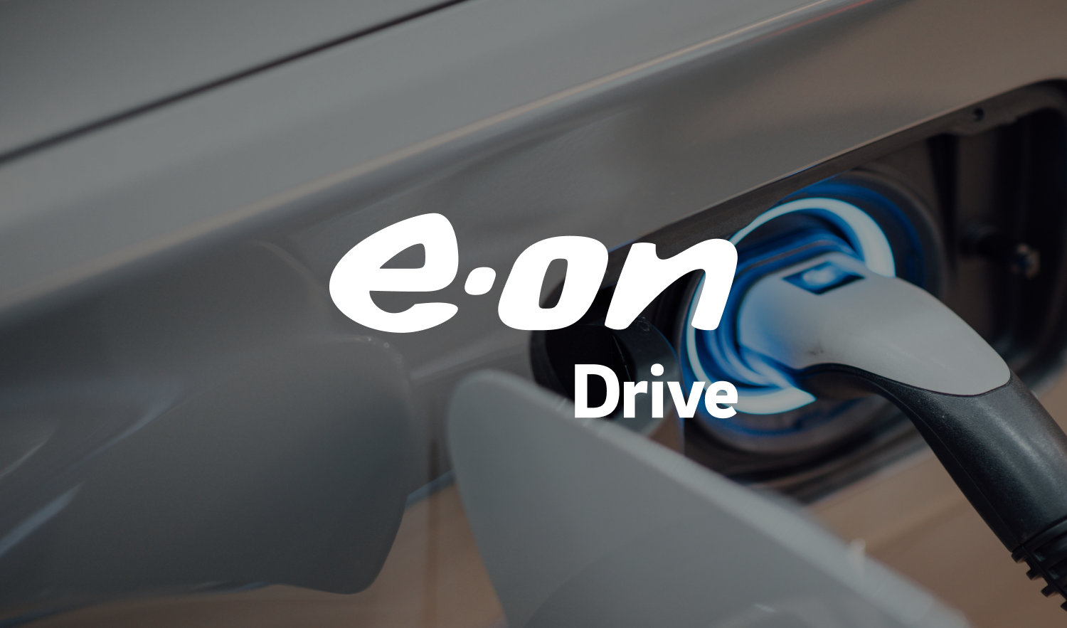 Close-up of an electric car charging port with a plugged-in charger, showing the words 'e-on Drive' overlaid.