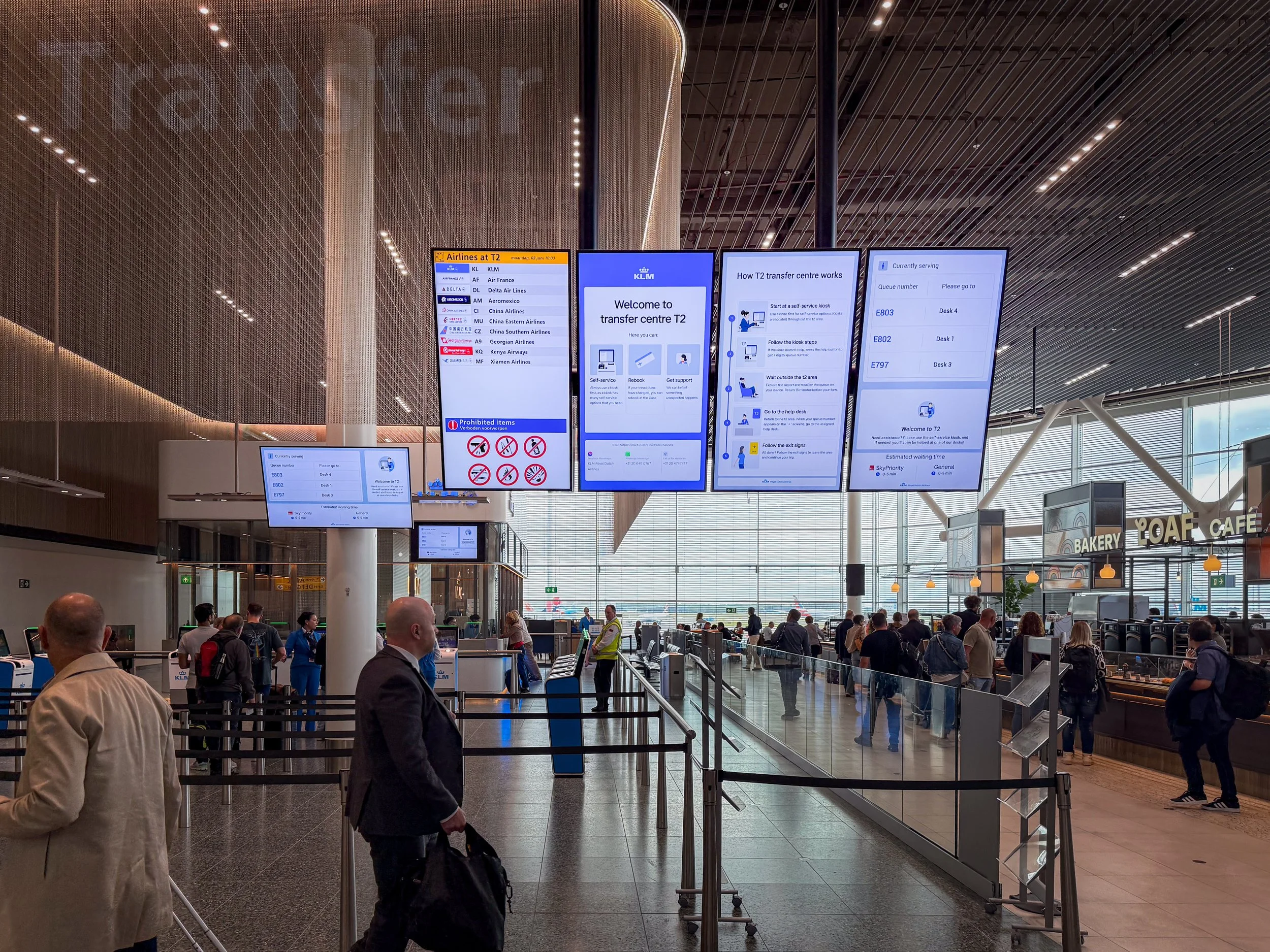 KLM digital information screens at Schiphol Airport's Transfer Centre showing flight information and wayfinding