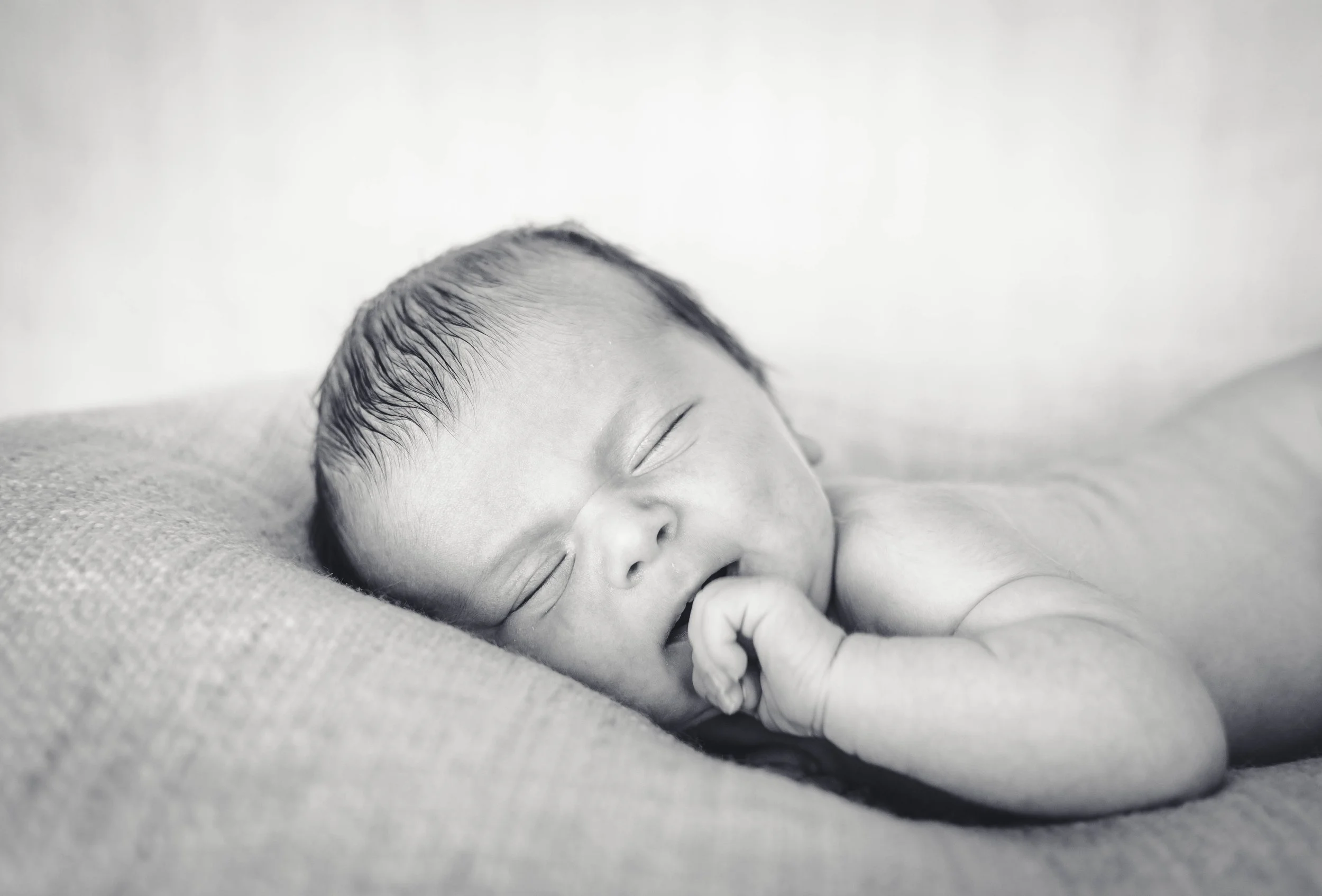 Zwart-wit foto van een slapende baby met gesloten ogen en een hand onder het gezicht.